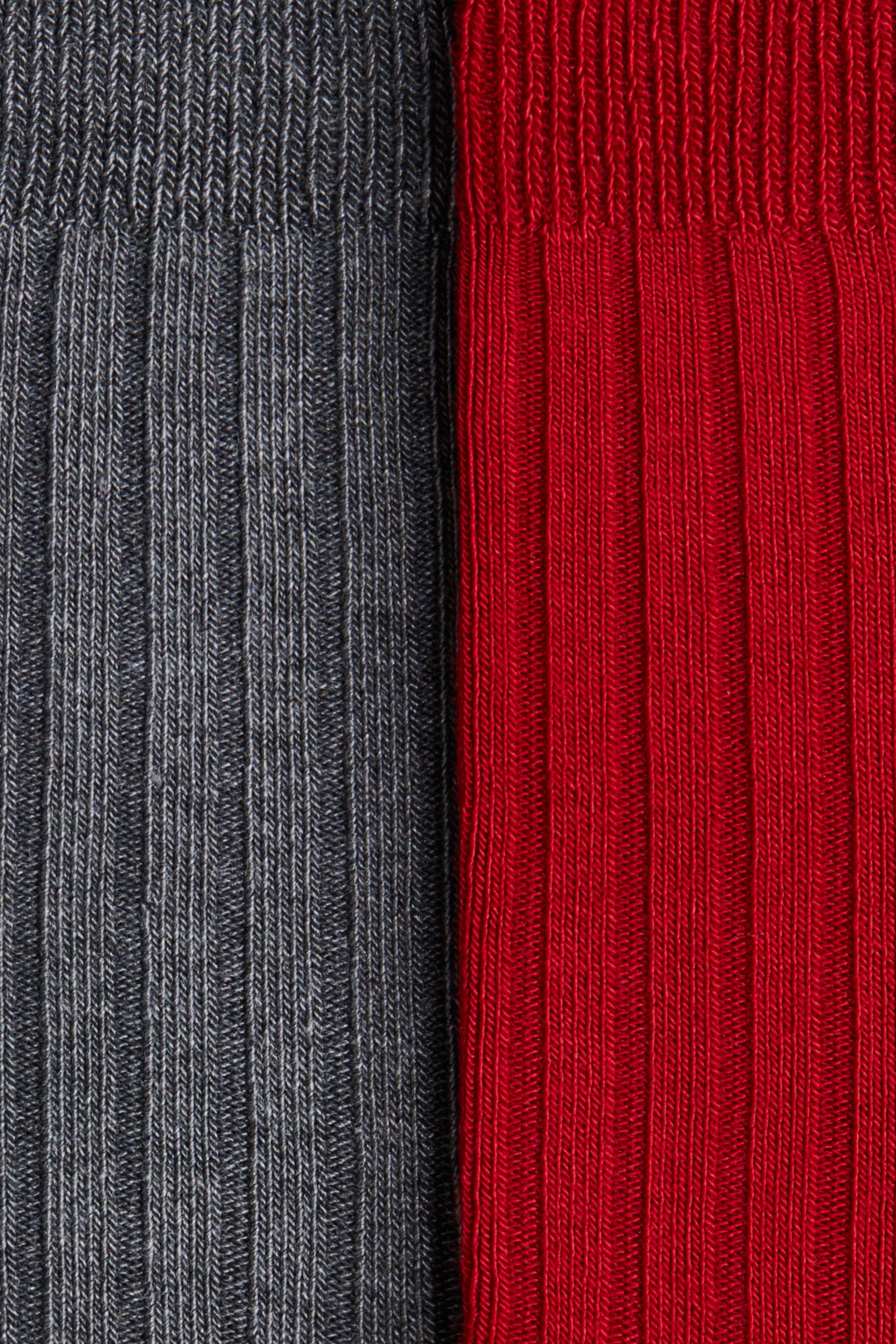 Zobacz większy obraz: Dwie prążkowane skarpety, jedna w ciemnoszarym kolorze, a druga w czerwonym, są prezentowane obok siebie. Obie skarpety mają delikatne pionowe prążki na całej długości i szerokie elastyczne mankiety na górze.