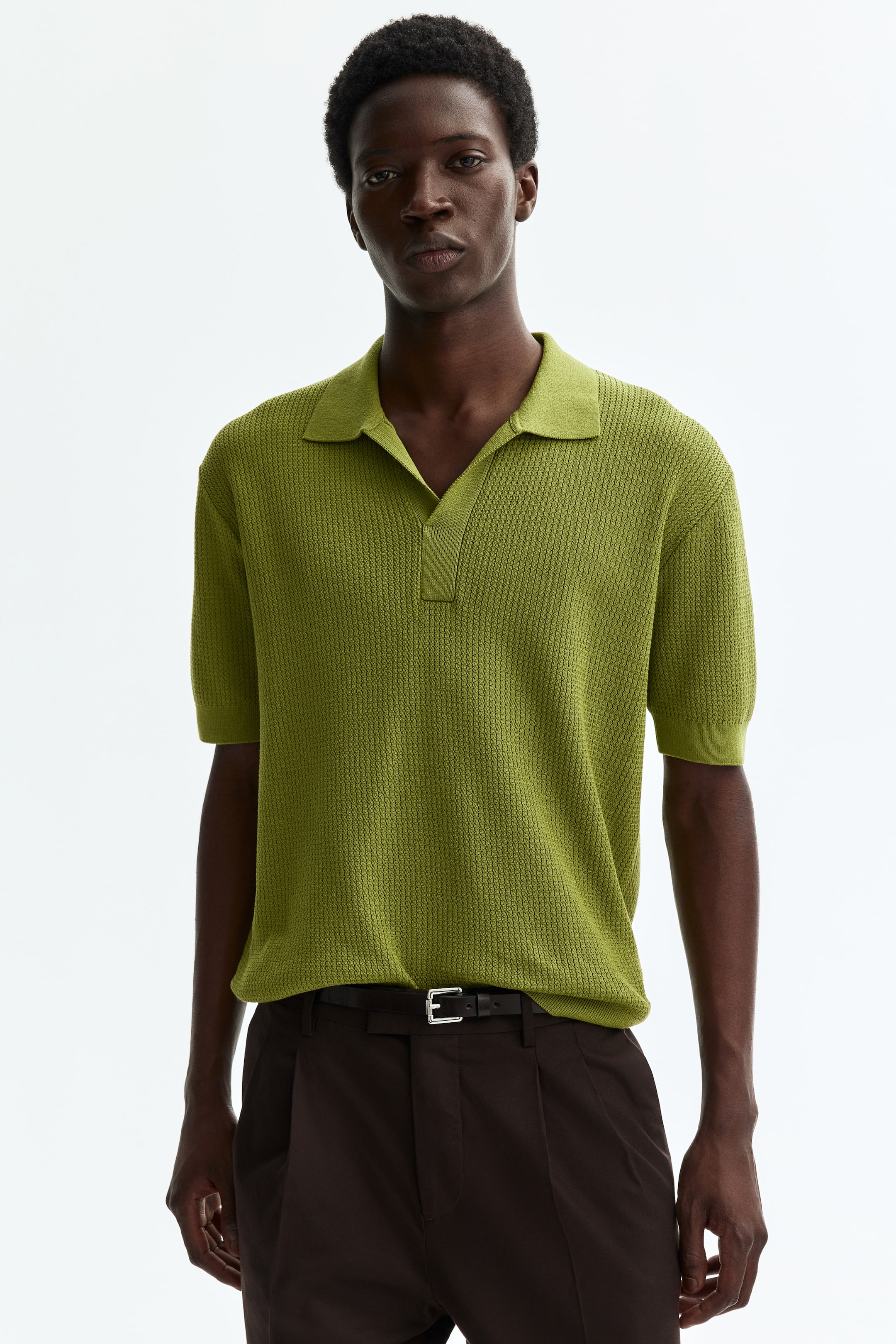 View larger image: An olive green knit polo shirt is showcased from the front, highlighting a relaxed fit, textured knit, spread collar, and a buttonless V-neck placket.