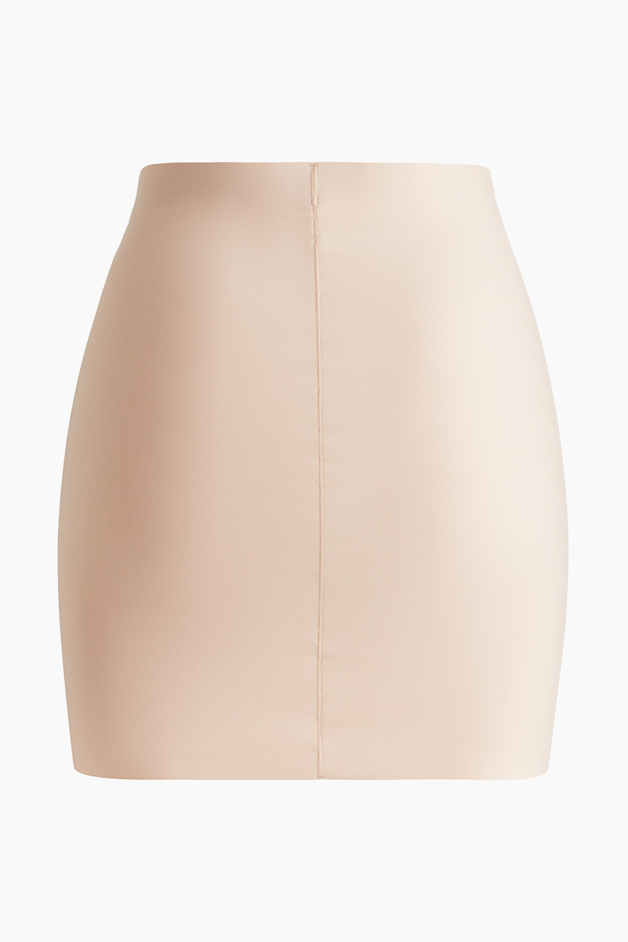 View larger image: A nude-colored mini skirt is facing front, displaying a close-fitting, high-waisted silhouette with a smooth, matte finish and a prominent vertical seam running down its center front.