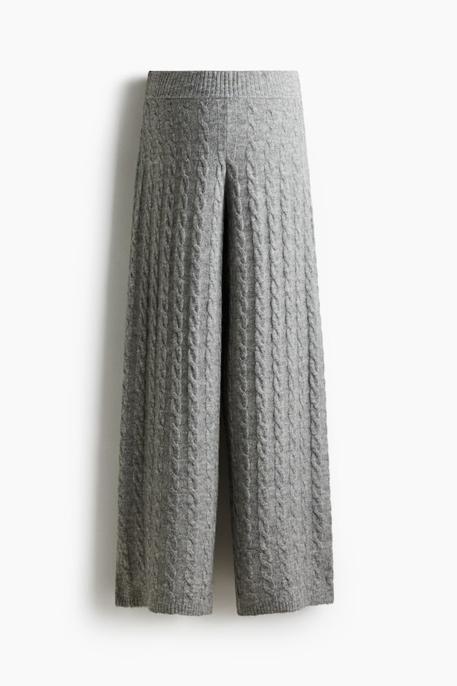 I pantaloni in maglia grigia presentano un motivo a treccia verticale su tutto il capo, che si estende da una cintura a coste fino agli orli a gamba larga. Sono presentati frontalmente. - 1