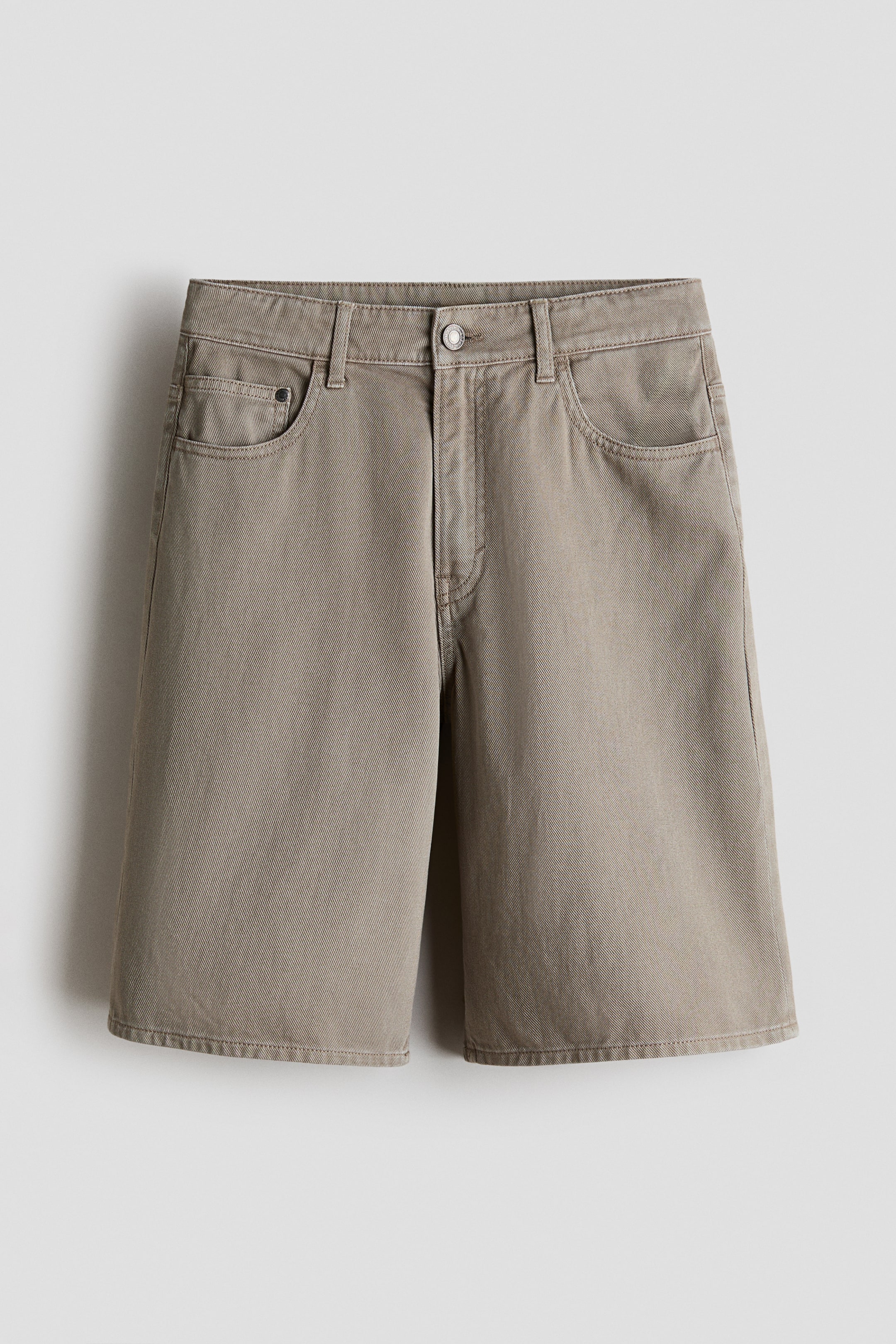 View larger image: Taupe cotton twill shorts are shown from the front, showcasing a mid-rise waist with belt loops, a front button, and a zipper fly. They include two front slash pockets and a small coin pocket, with a straight, wide-leg cut that extends just above the knee.