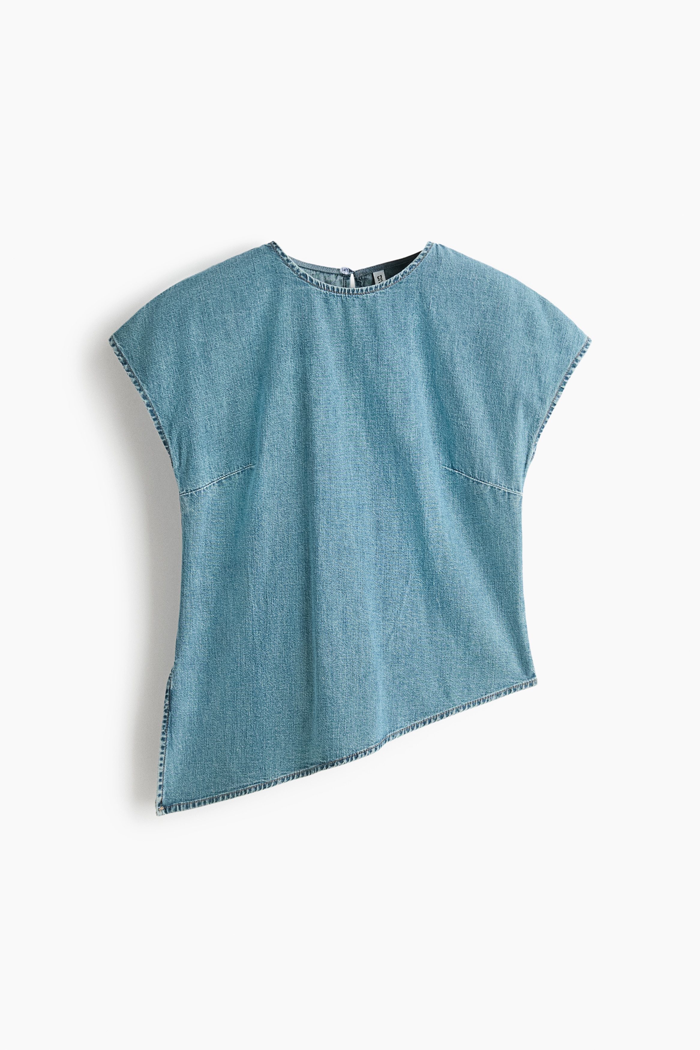 A blue denim top featuring a round neckline, cap sleeves, and an asymmetrical hem with a high side slit is worn by the model. The top is styled with beige drawstring trousers.