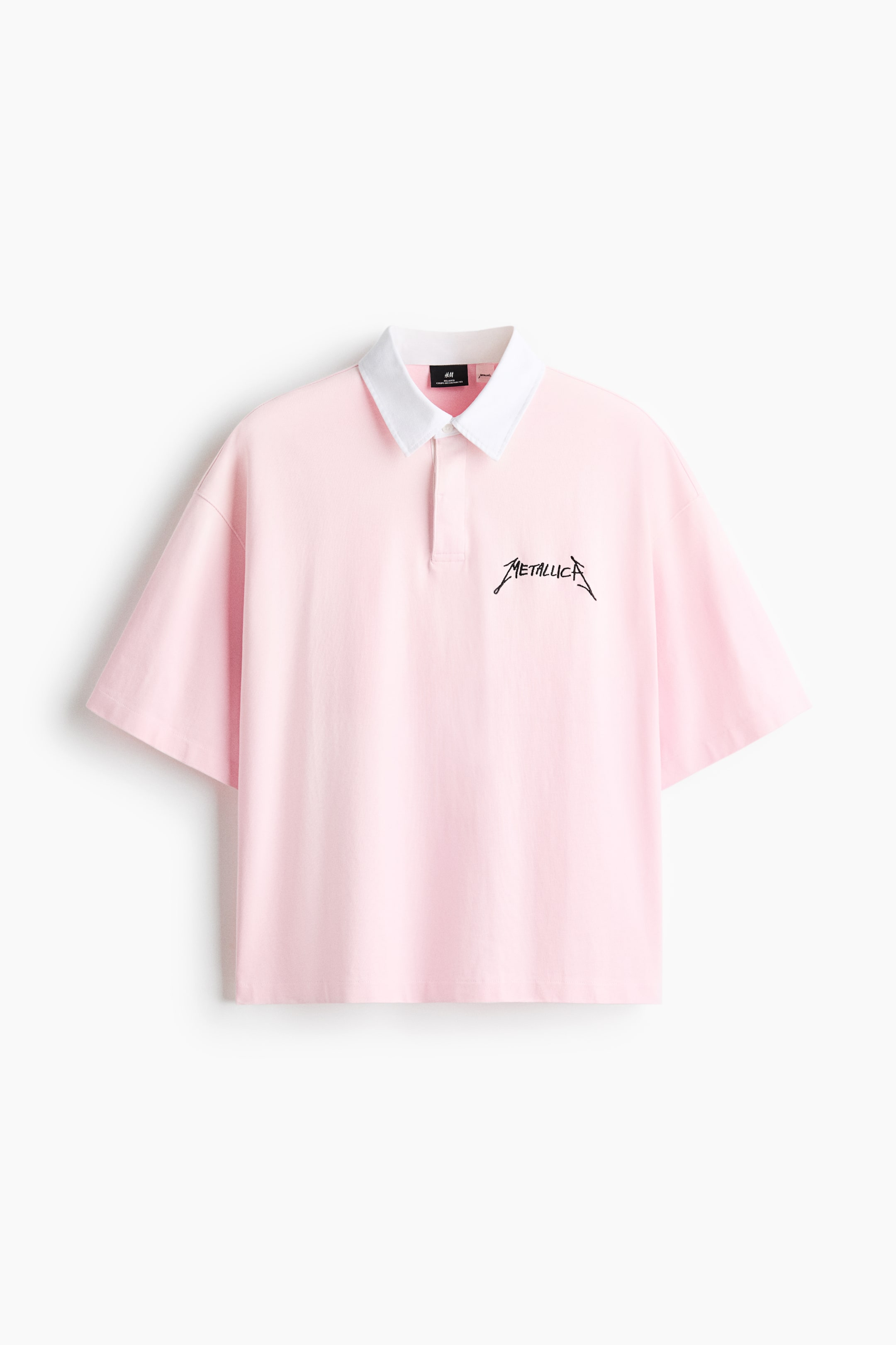 View larger image: The pink polo shirt is shown in a front view, featuring a contrasting white collar and a two-button placket. A black "Metallica" logo appears on the left chest, and the shirt is designed with loose-fitting short sleeves and a straight hem.