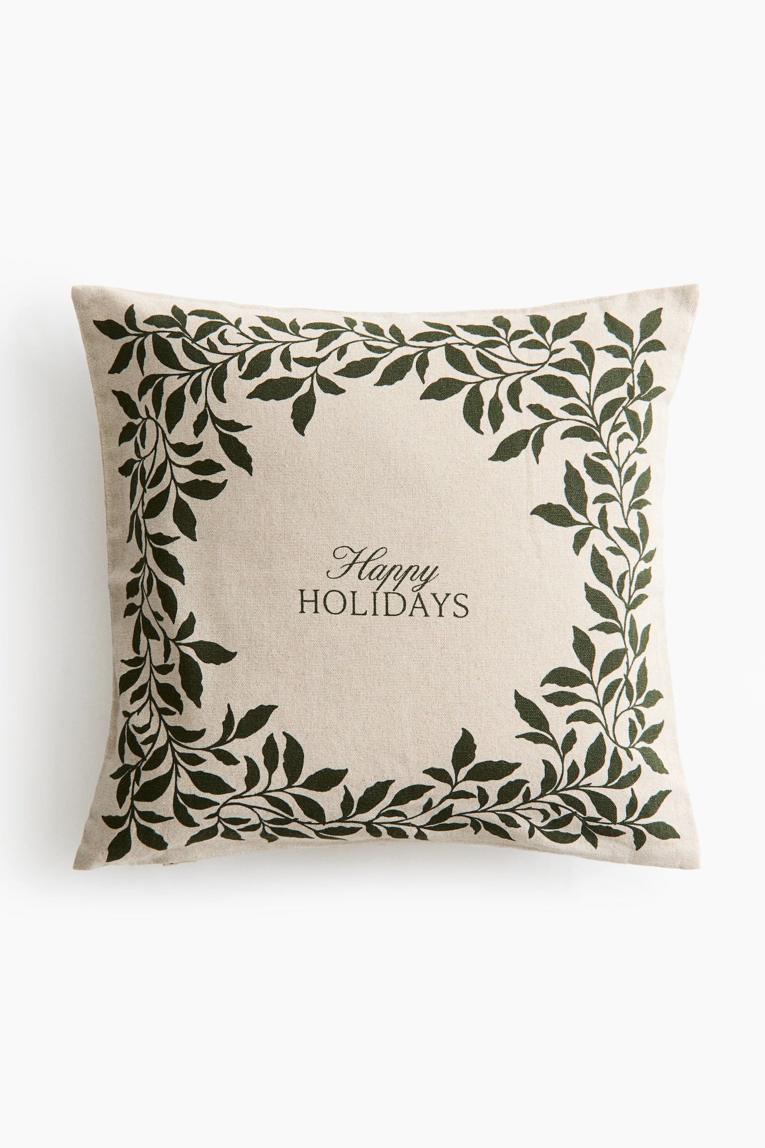 Una fodera per cuscino quadrata in tessuto misto lino beige è mostrata frontalmente, con un bordo di tralci fogliati verde scuro stampato lungo i bordi. Al centro compaiono le parole "Happy HOLIDAYS" stampate in caratteri corsivi e serif verde scuro.