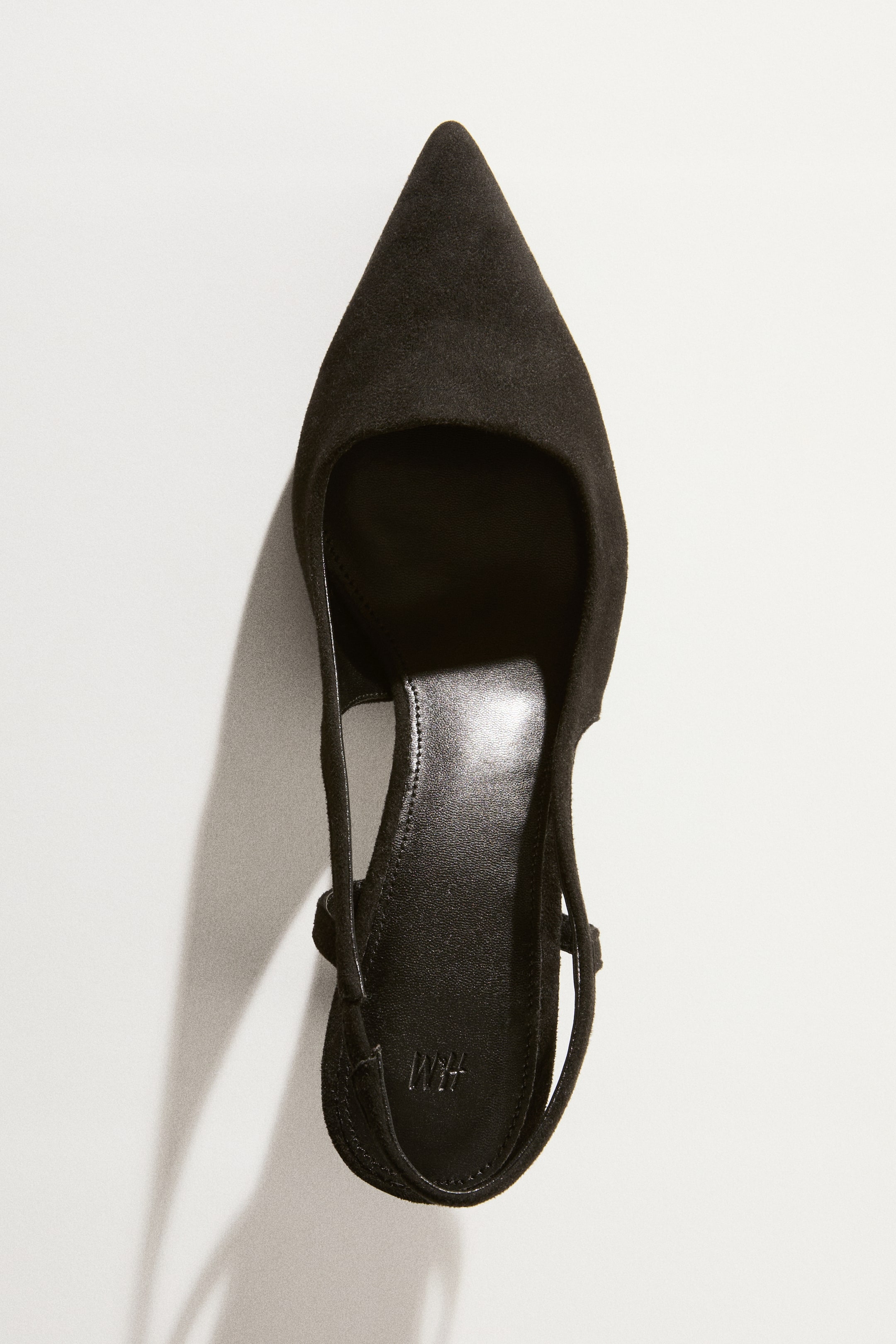 Xem ảnh lớn hơn: Một đôi giày slingback màu đen, được làm từ vải phủ, với mũi nhọn, quai gót mảnh có chun co giãn ở một bên, và gót thấp kitten heel.