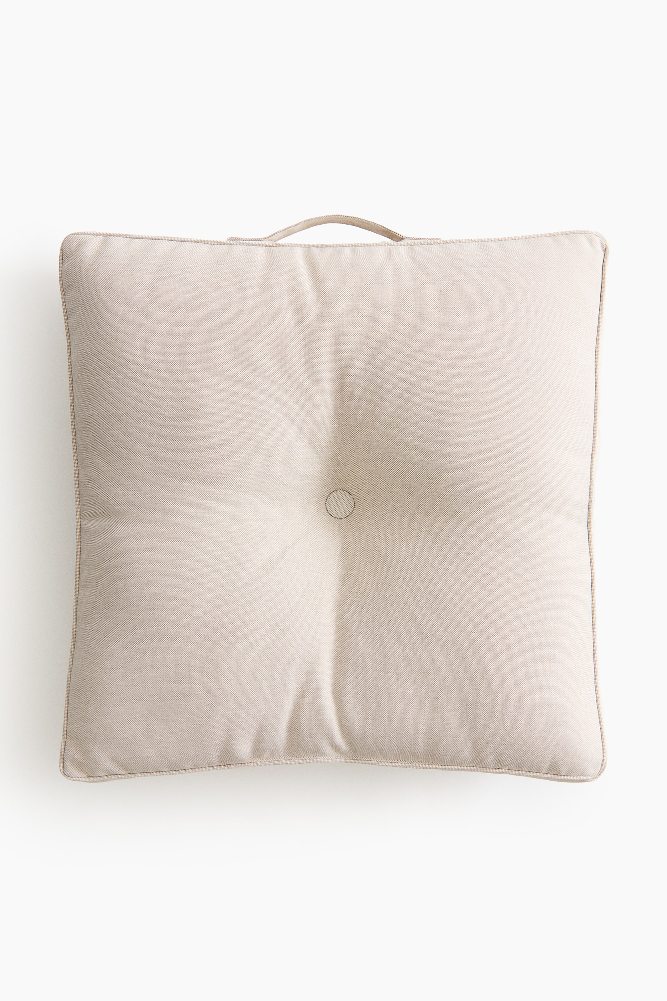View larger image: A square, light beige cushion is displayed from the front, showcasing piped edges, a central tuft, and a fabric loop handle on its top edge.