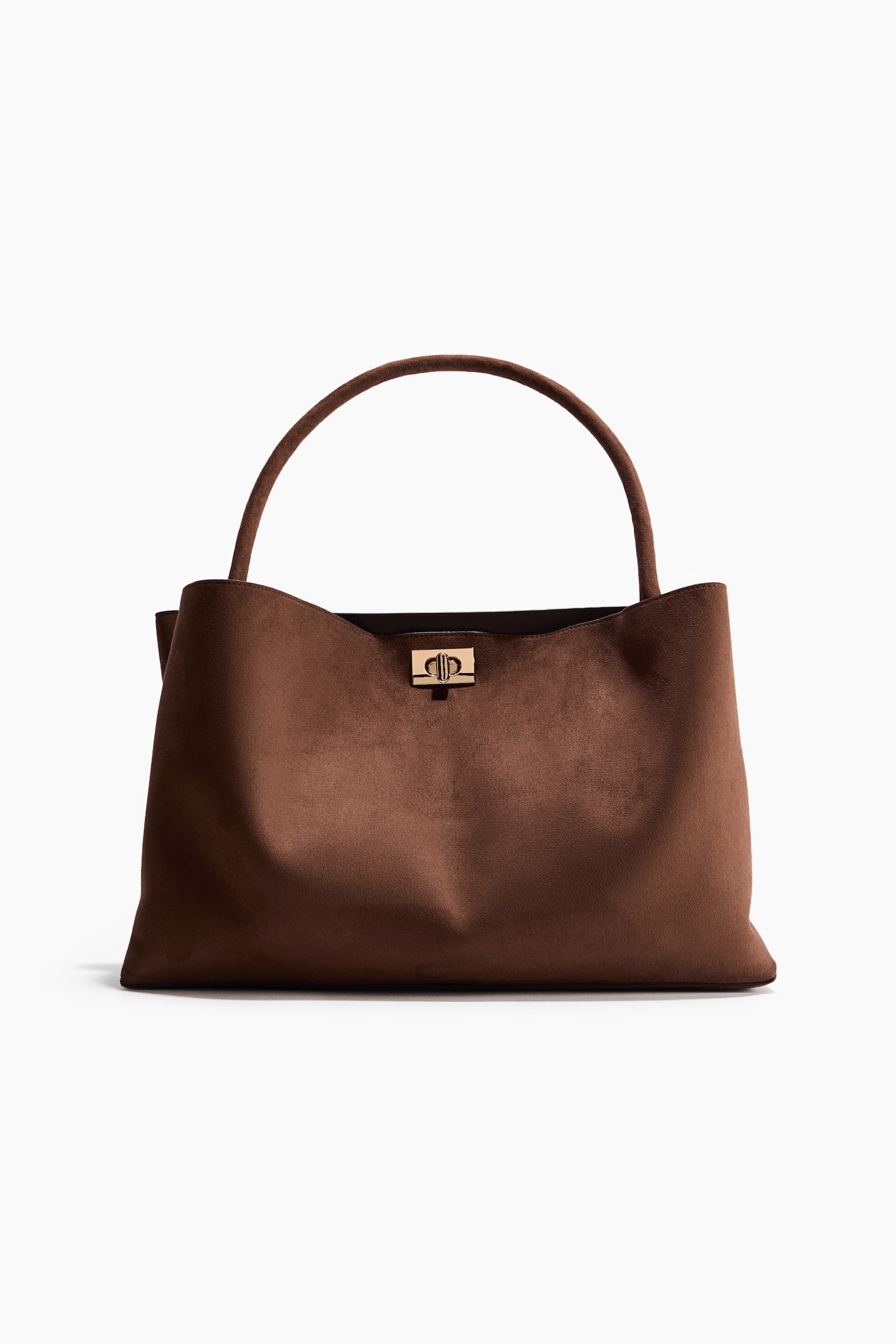 Un bolso marrón está orientado hacia adelante, con una textura similar a la gamuza y una sola asa superior curva. Un cierre dorado prominente con un diseño entrelazado asegura el cierre frontal. El bolso muestra una silueta suave y sin estructura con una base ancha. - 1