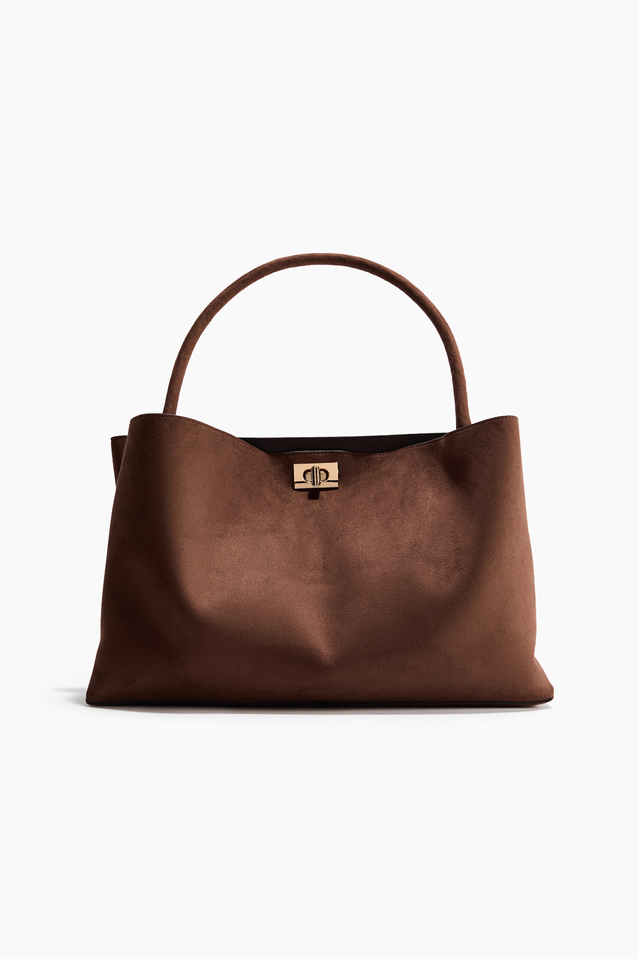 Ver imagen más grande: Un bolso marrón está orientado hacia adelante, con una textura similar al ante y un único asa superior curvada. Un cierre dorado prominente con un diseño entrelazado asegura el cierre frontal. El bolso presenta una silueta suave y sin estructura, con una base ancha.