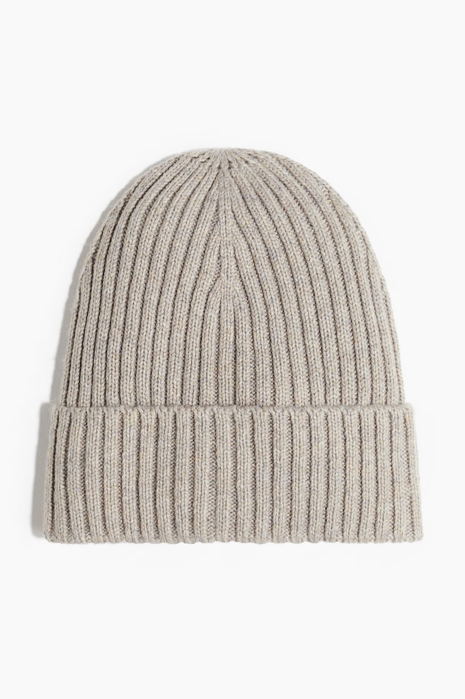 A light beige marled ribbed knit beanie is presented from the front, featuring a wide folded cuff. - 1