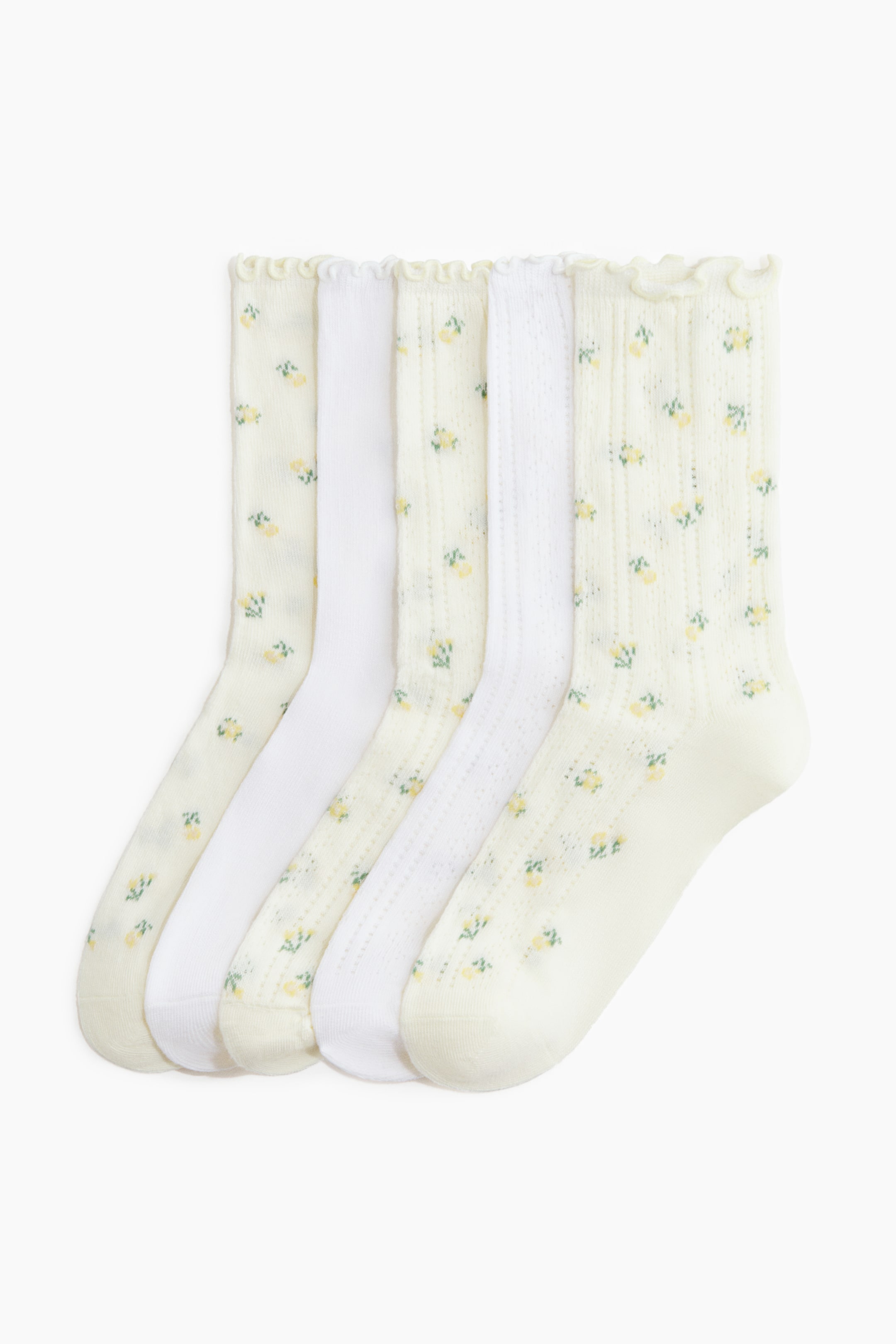 View larger image: Five pairs of socks are displayed front-facing. Three pairs feature an off-white pointelle knit with a small yellow floral pattern, while one pair shows a plain white knit, and another displays a solid white pointelle knit. All socks are finished with elasticated, frill-trimmed tops.