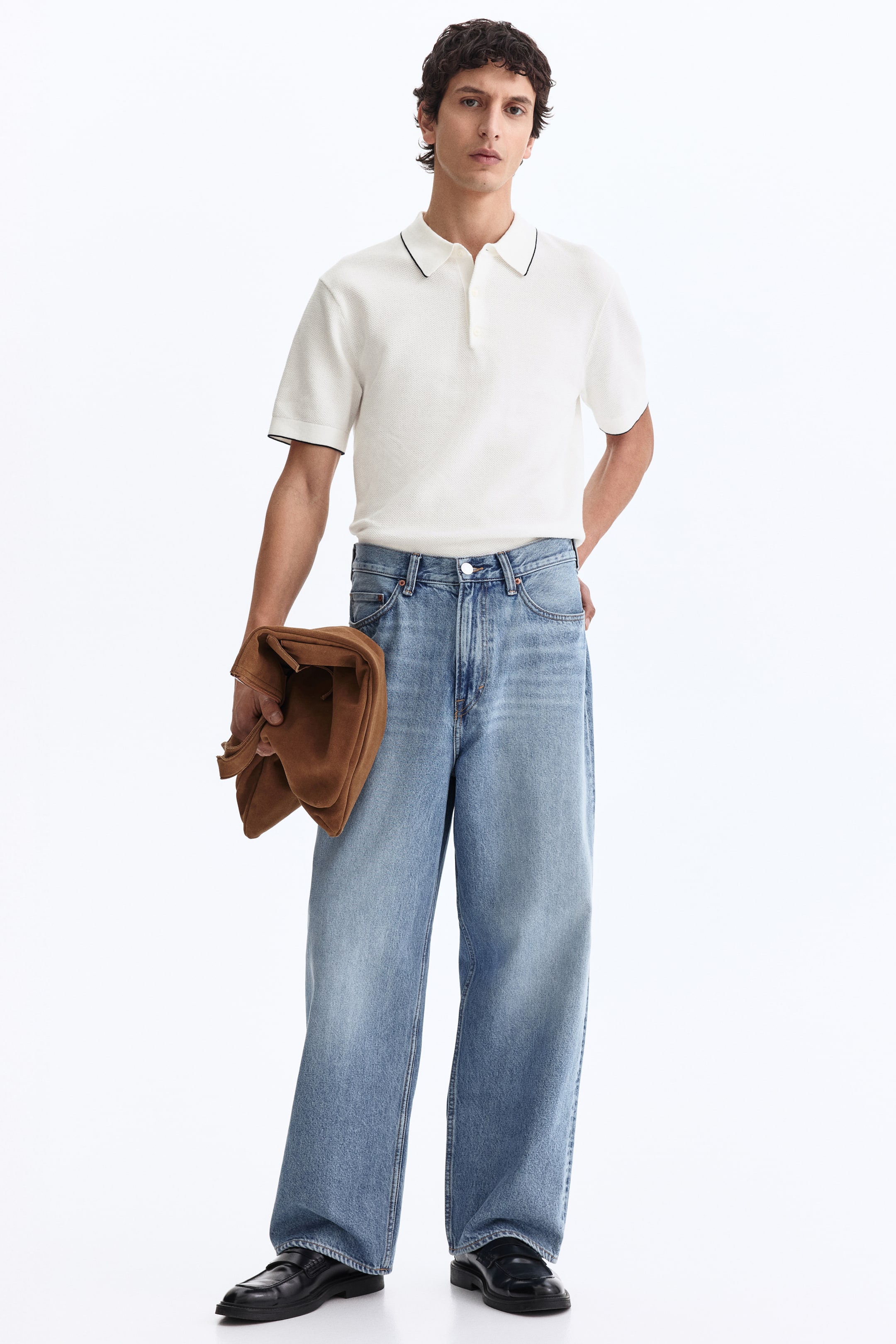 Ampliar la imagen: Los jeans de mezclilla de corte holgado con lavado claro presentan un tono azul deslavado y piernas anchas. Cuentan con el diseño estándar de cinco bolsillos y se acumulan ligeramente en los tobillos.