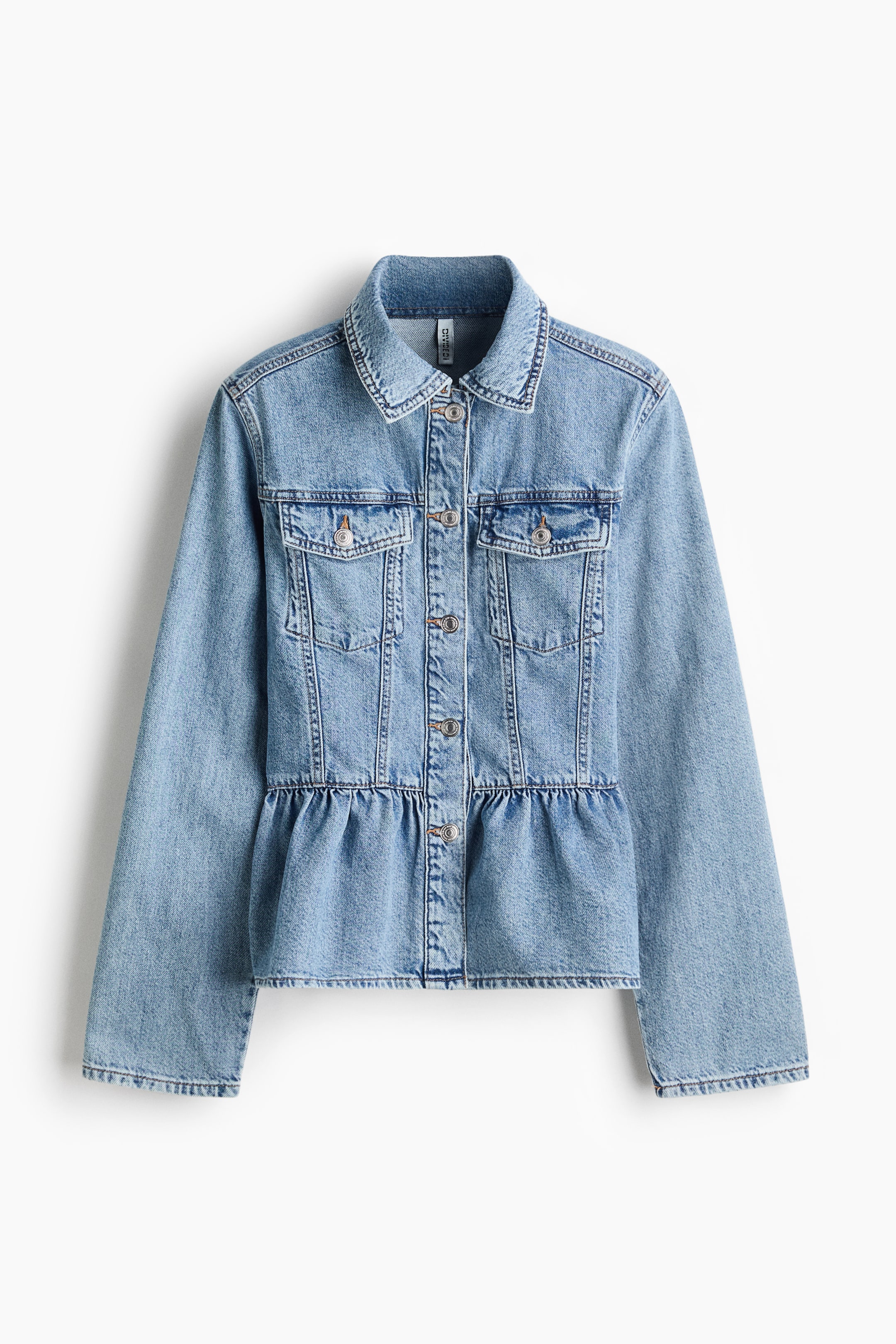 View larger image: A light blue rigid cotton denim jacket is shown from the front, featuring a collar, buttons down the front, two flap chest pockets with buttons, a gathered seam at the waist, and a flared peplum.