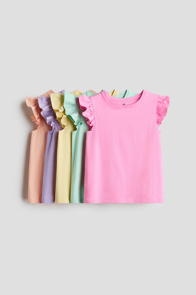 Five soft cotton jersey tops are lined up, each featuring a round, rib-trimmed neckline and flutter sleeves. The tops are presented in a range of pastel colors, with the pink top clearly facing front. - 1