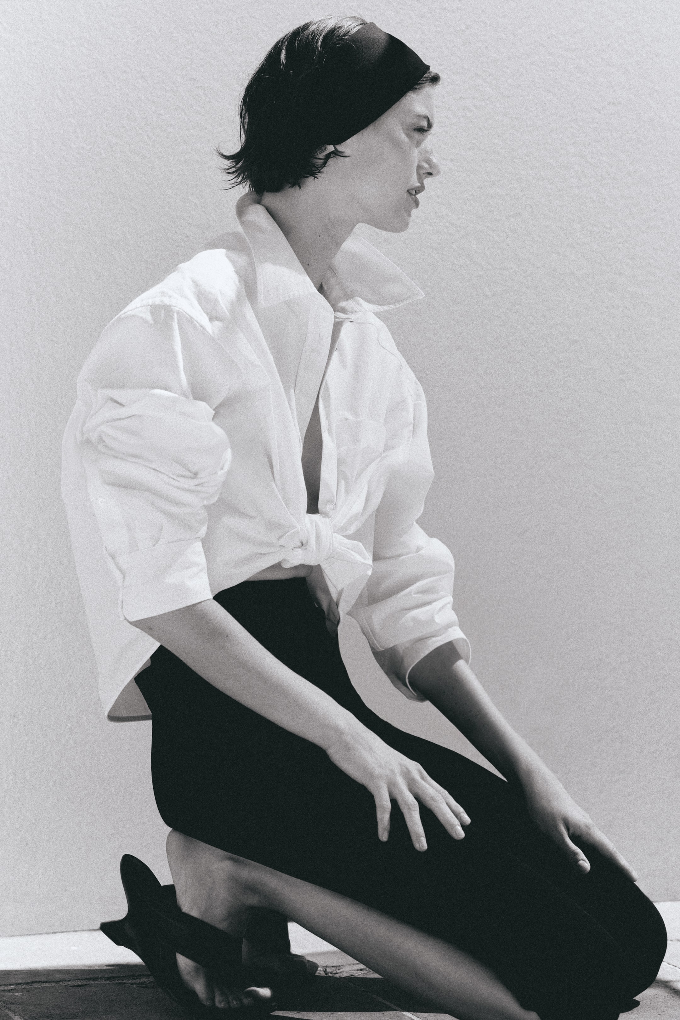 View larger image: 3/4-length leggings in heavy jersey with concealed elasticated waistband are being worn by the model, featuring sewn-in creases down the front and small slits at the hems. The model is kneeling, showcasing the leggings' length and hem details.