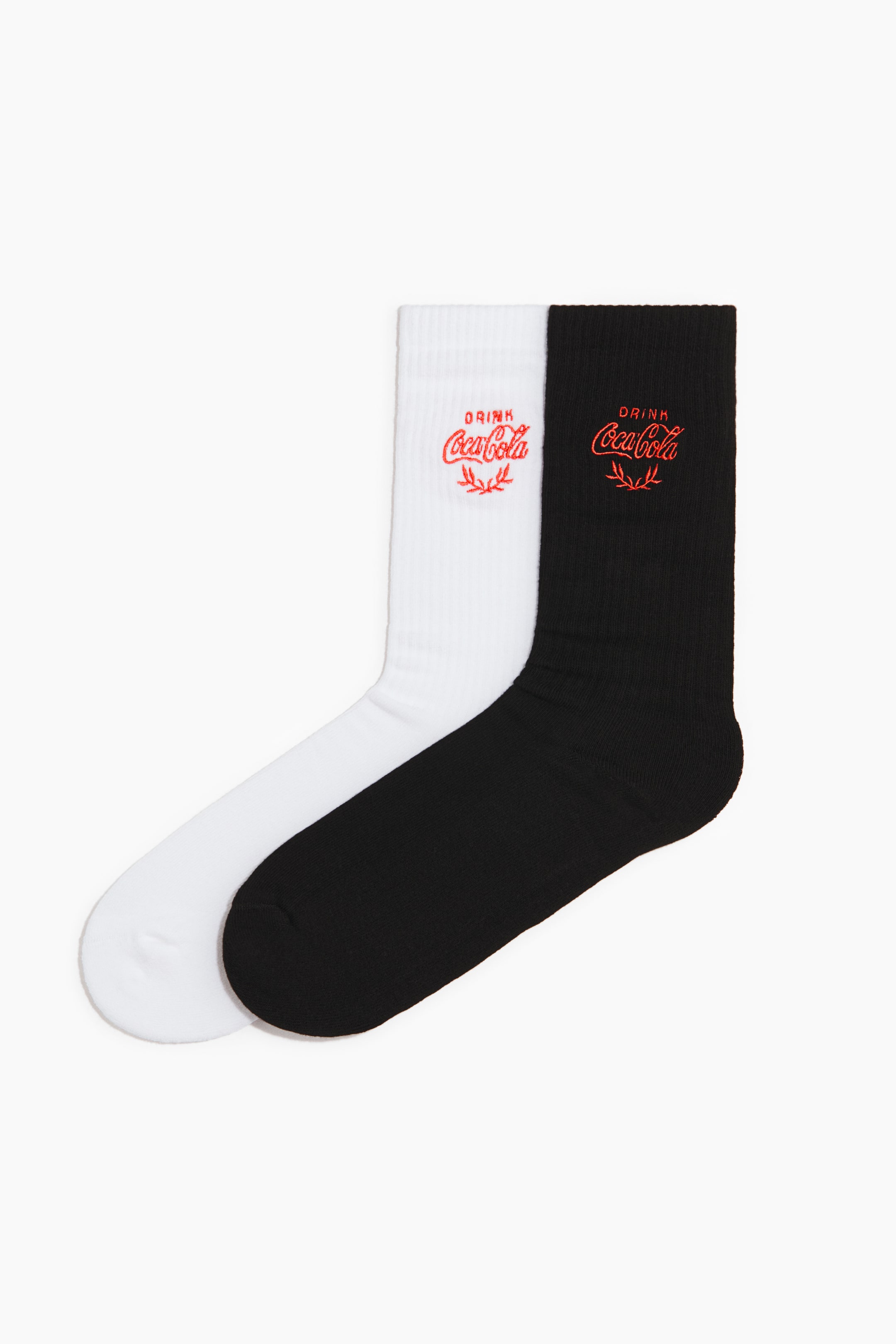 View larger image: Two socks, crafted from a soft, fine-knit cotton blend, are lying side-by-side, with one white and one black sock. Both feature a high, ribbed shaft with a red 'DRINK Coca-Cola' motif appearing on the front.