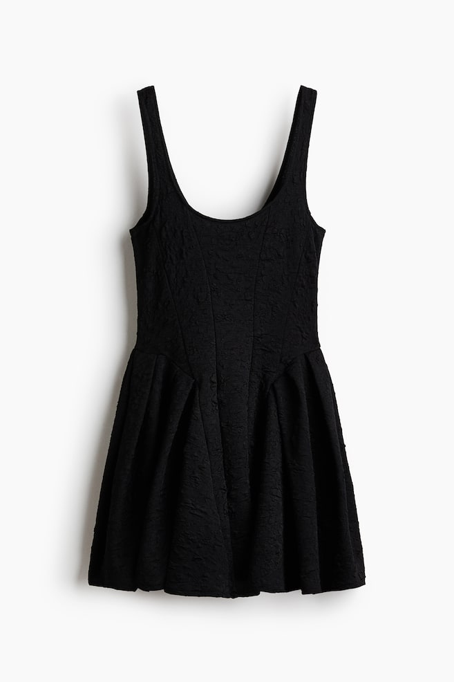 Un vestido negro sin mangas cuelga de frente, mostrando un escote amplio y profundo, tirantes anchos y un corpiÃ±o ajustado con costuras verticales en panel. El vestido exhibe una tela texturizada y arrugada, asÃ­ como una falda plisada y acampanada. - 1