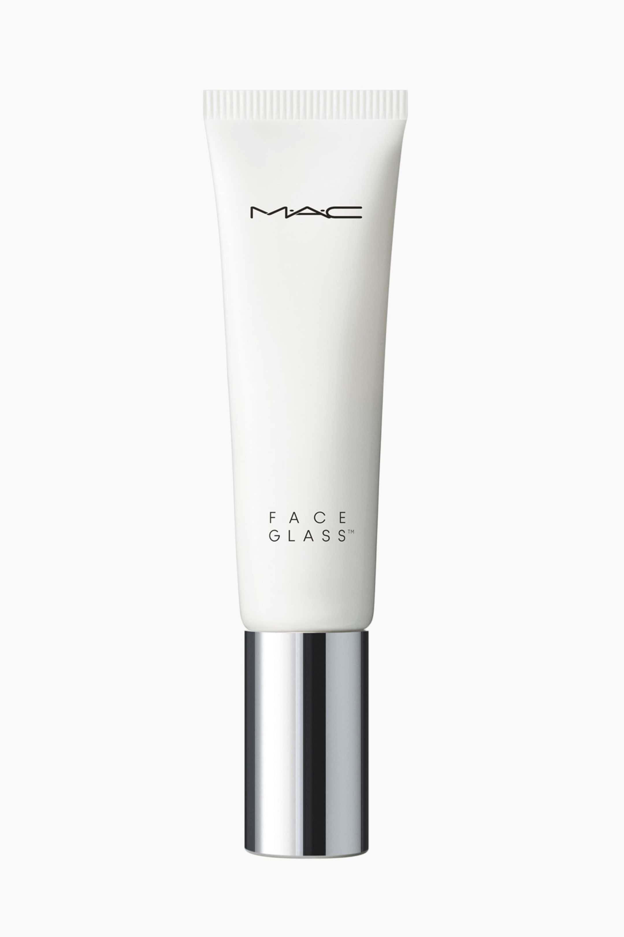 Se større billede: En klemmetube med MAC Face Glass står lodret og fremviser en mat hvid krop og en cylindrisk, reflekterende sølvmetalisk hætte i bunden. Tuben har det sorte MAC-logo nær den riflede topkrimp og ordene "FACE GLASS" trykt nær bunden i en bogstavspacende sort skrifttype.