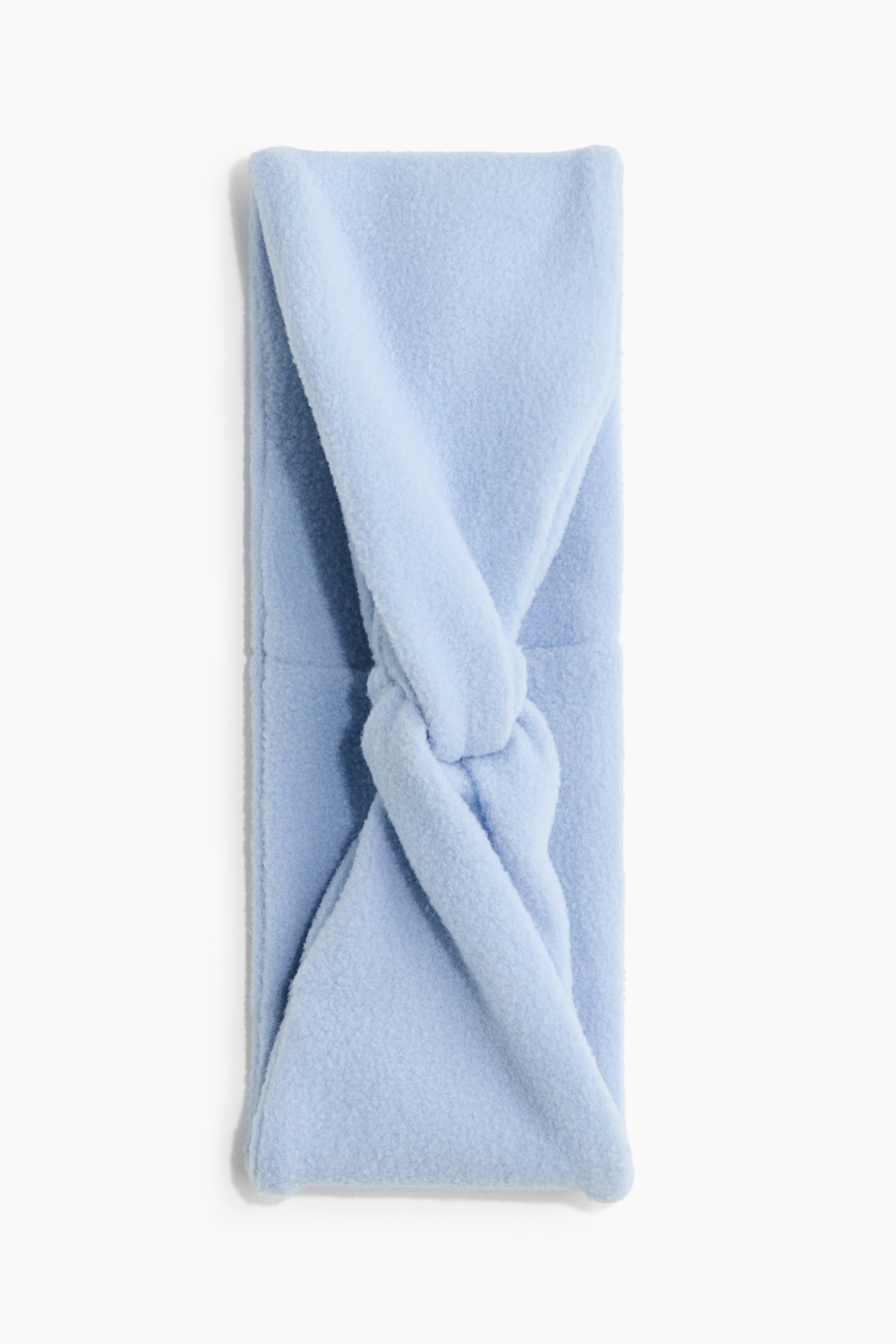 View larger image: A light blue fleece headband is lying flat, showcasing its soft, textured fabric and a twisted knot detail at the centre front.