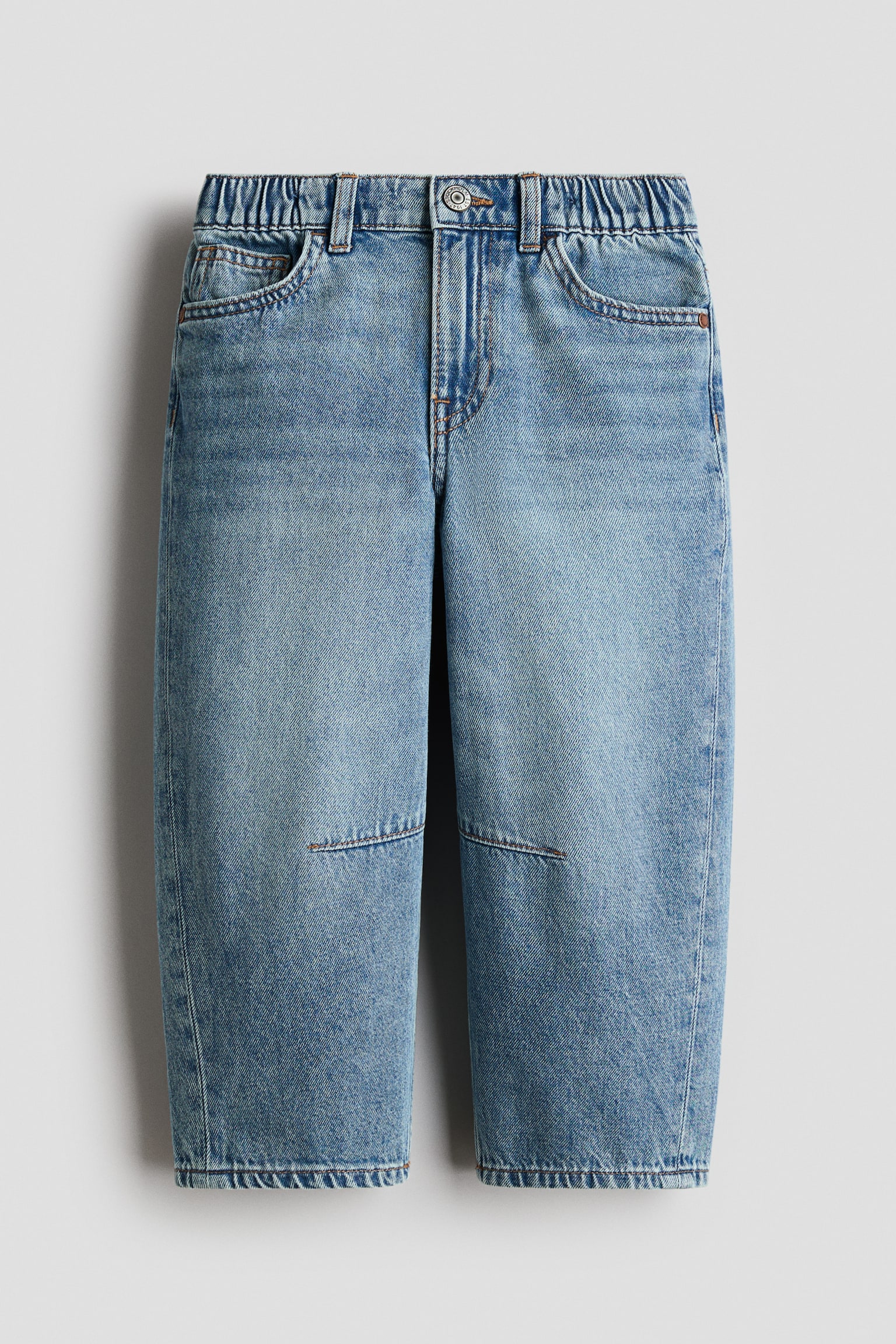 Os jeans de ganga azul claro apresentam um fecho frontal com botão e fecho de correr, uma cintura elástica na parte de trás e presilhas para cinto. Exibem dois bolsos frontais curvados, um bolso para moedas e detalhes de costura que se assemelham a joelheiras nas pernas largas e cortadas. - 1