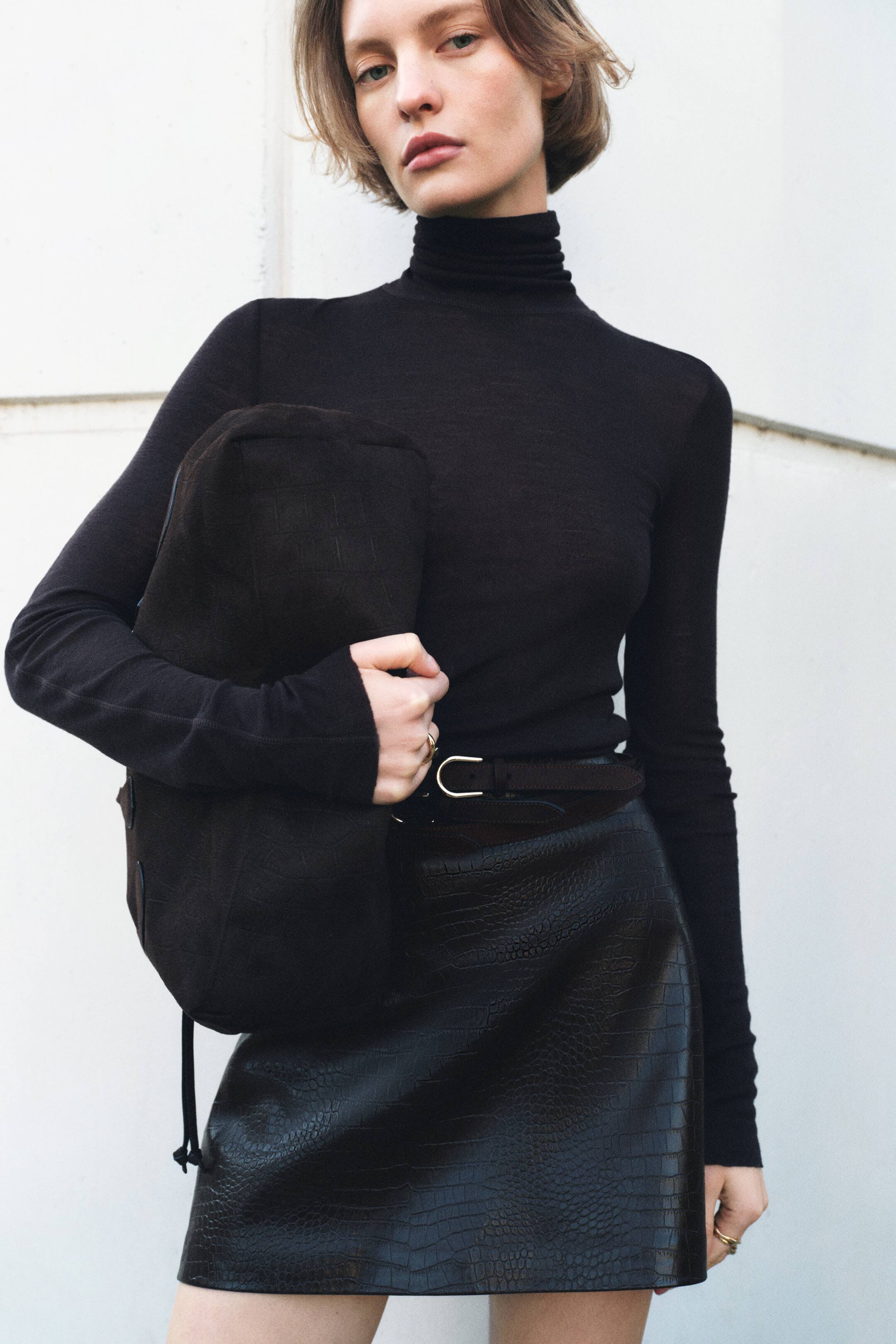 הצגת תמונה גדולה יותר: חולצת גולף שחורה נלבשת, עם צווארון גבוה ומקופל ושרוולים ארוכים וצמודים מבד סריג חלק ועדין.