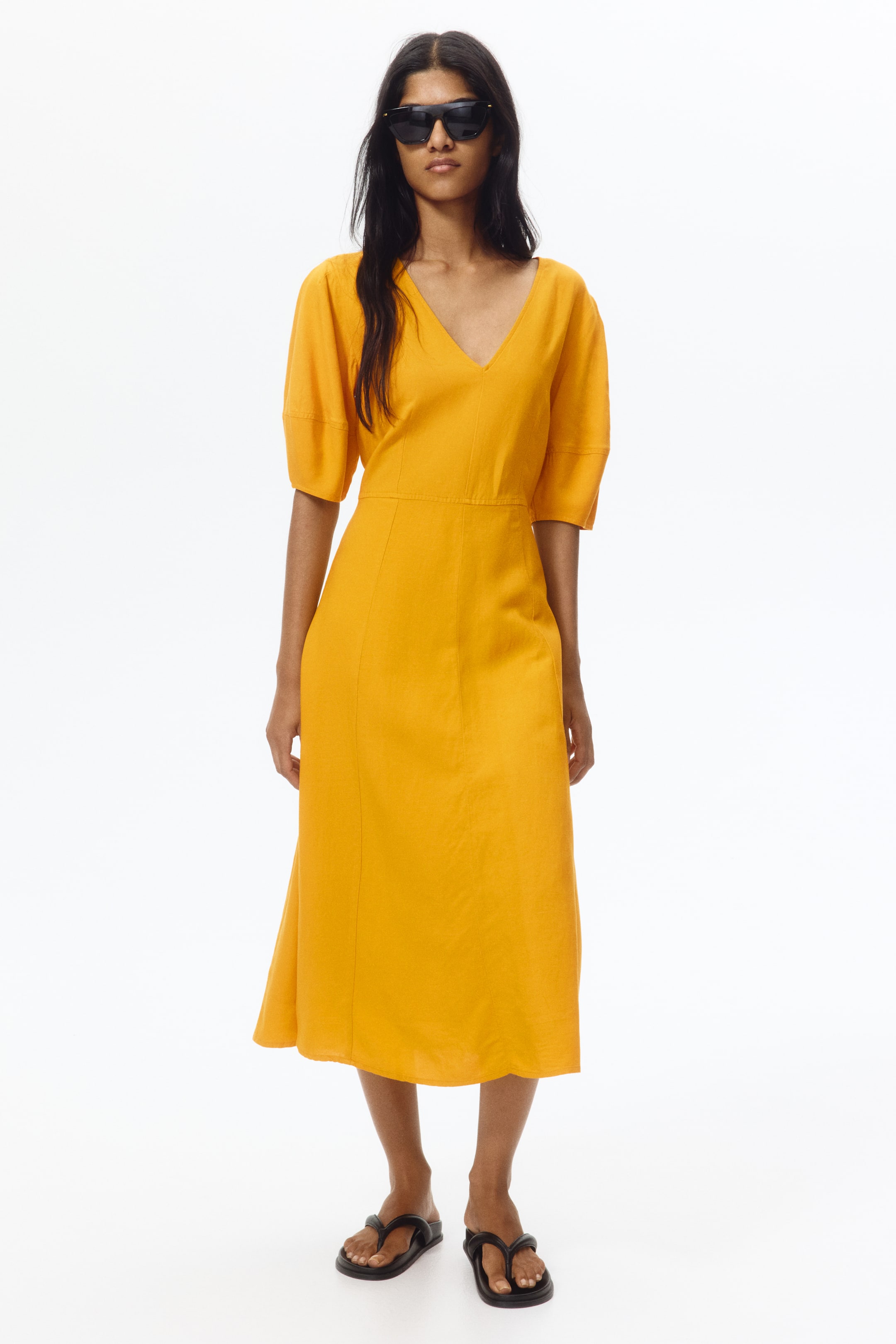 View larger image: A yellow midi dress showcasing a V-neckline and short, puffed sleeves. Crafted with a fitted bodice, visible seam details, and a flared midi skirt in a textured fabric.