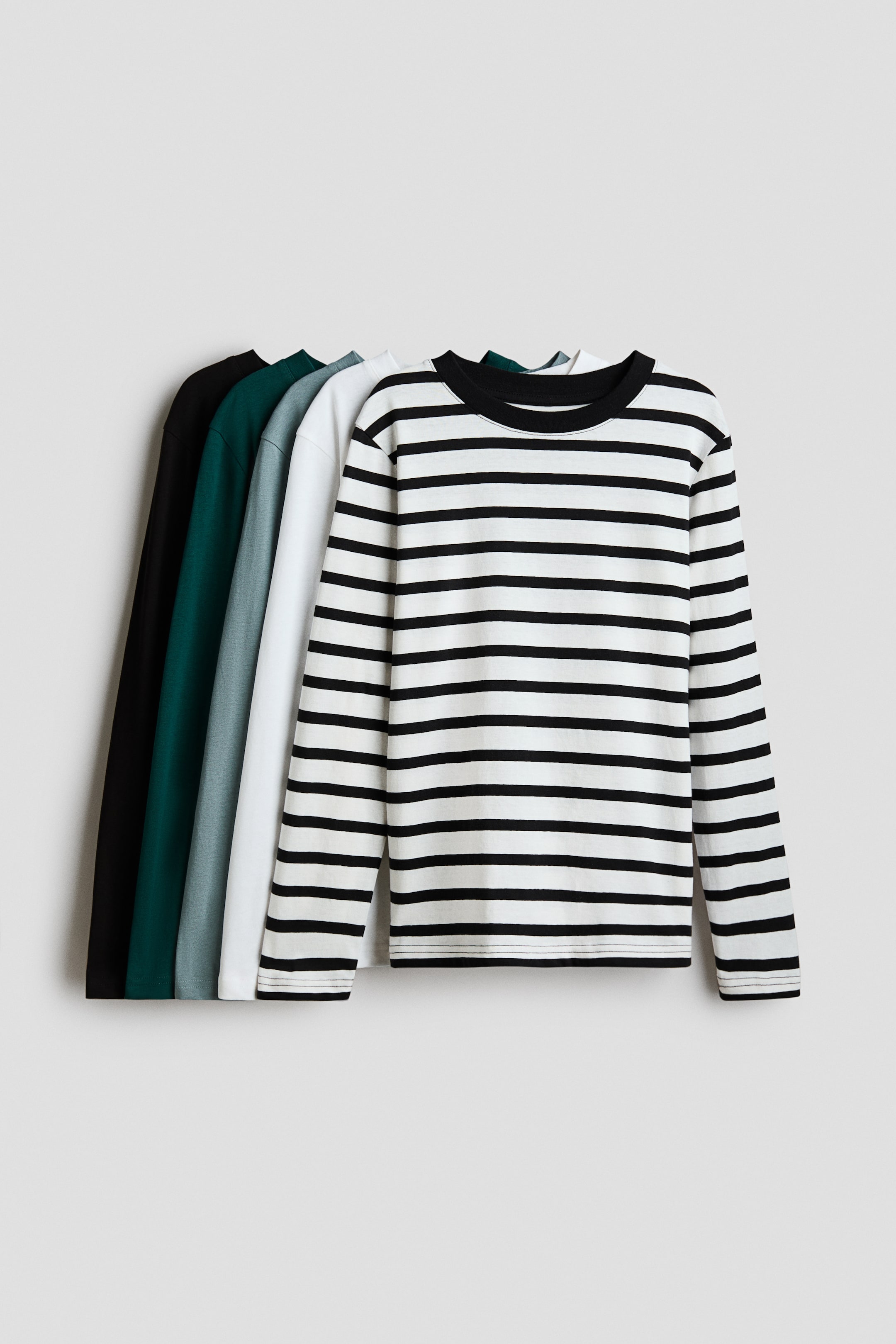 View larger image: Long-sleeved t-shirts in soft cotton jersey with a round, rib-trimmed neckline are arranged, displaying multiple colour options. The front t-shirt features a white and black horizontal stripe pattern with a black rib-trimmed neckline, while other solid-coloured t-shirts are visible behind it in white, light grey, dark green, and black.