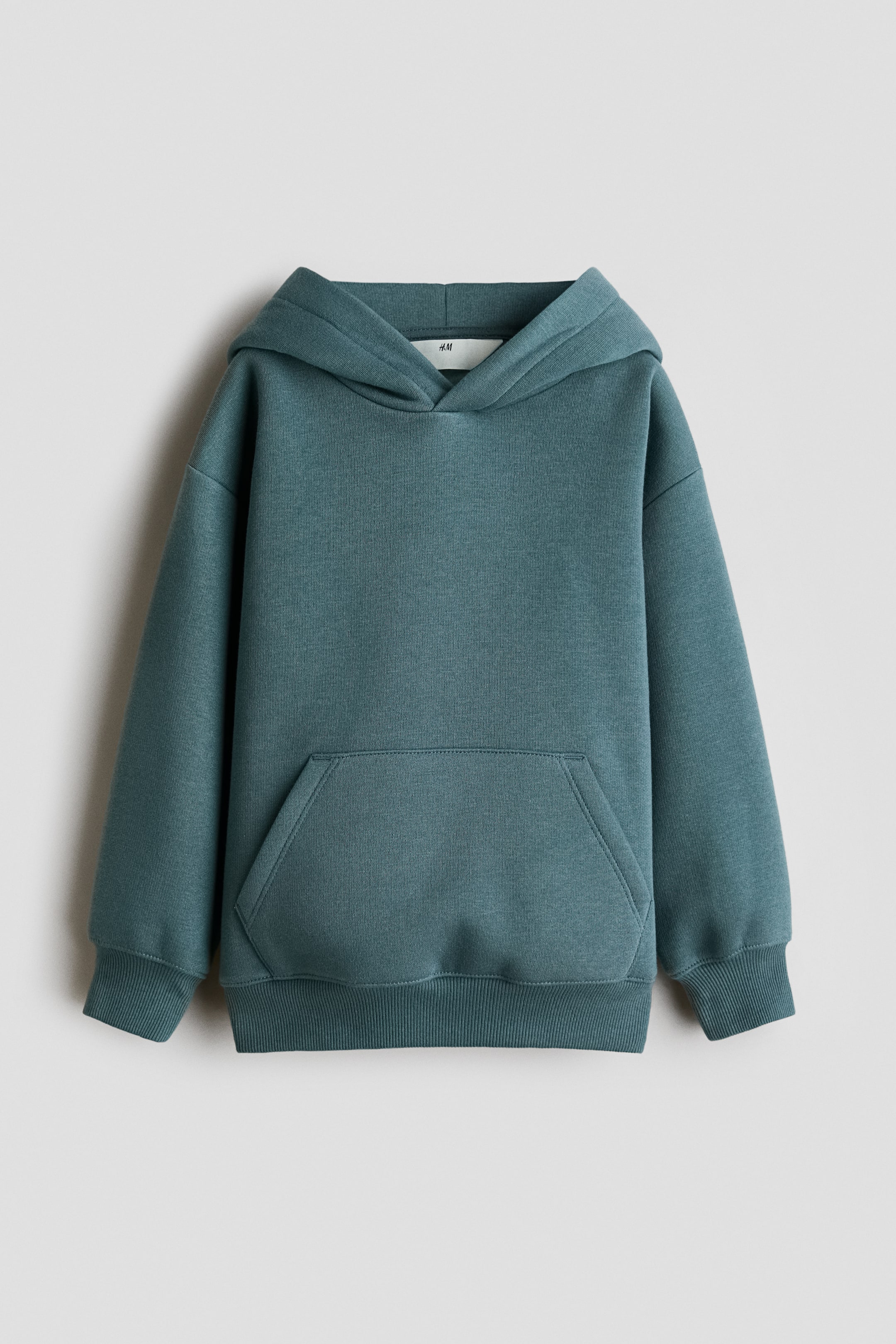 View larger image: A teal fleece hoodie is shown from the front, featuring a jersey-lined hood with a wrapover front and gently dropped shoulders. It showcases a front kangaroo pocket and long sleeves with wide ribbed trims at the cuffs and hem.