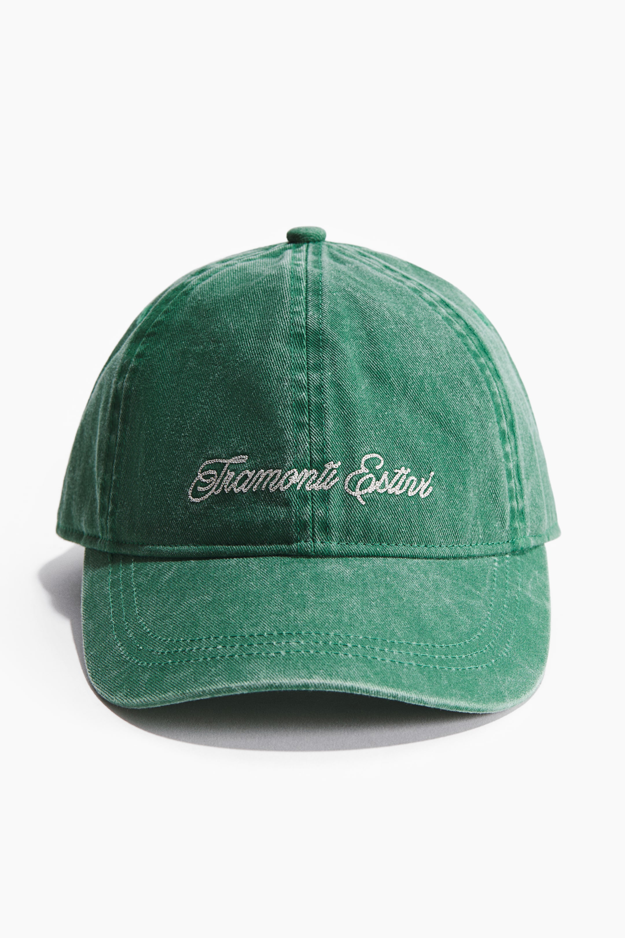 Zobacz większy obraz: Zielona czapka z bawełnianego splotu skośnego z efektem sprania, ozdobiona jasnym napisem "Tramonti Estivi" wyhaftowanym na PRZODZIE, z zaokrąglonym guzikiem na szczycie korony.