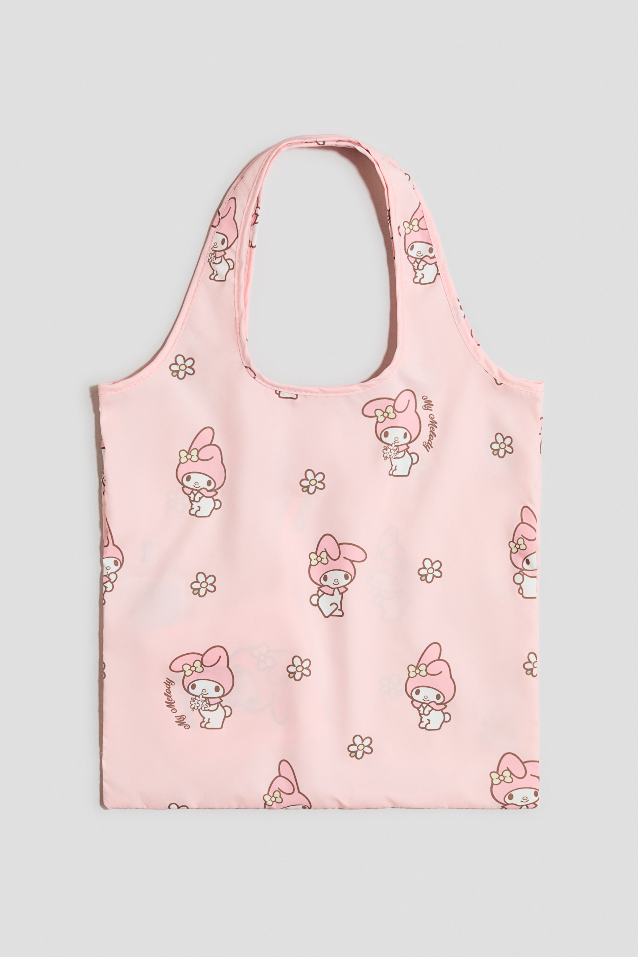 Преглед на по-голямо изображение: Розова тоут-чанта е показана отпред, с повтарящ се мотив с персонажа "My Melody" и малки кафяви цветенца с контури. Дизайнът включва две широки интегрирани горни дръжки.