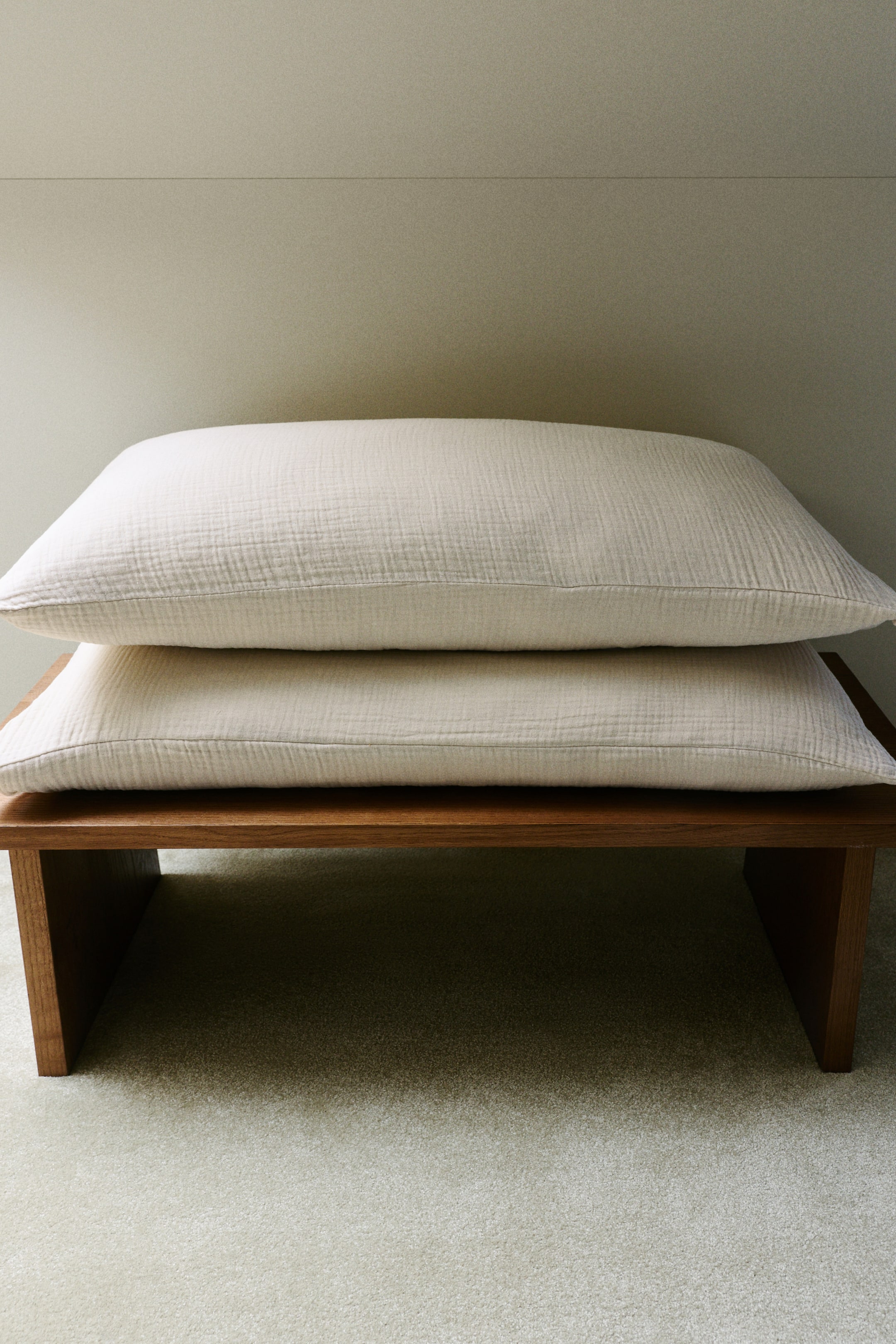 View larger image: Two pillowcases crafted from soft cotton muslin, featuring an envelope opening, are neatly stacked, one atop the other. They exhibit a light cream hue with a gentle crinkled texture gracing their front surfaces.