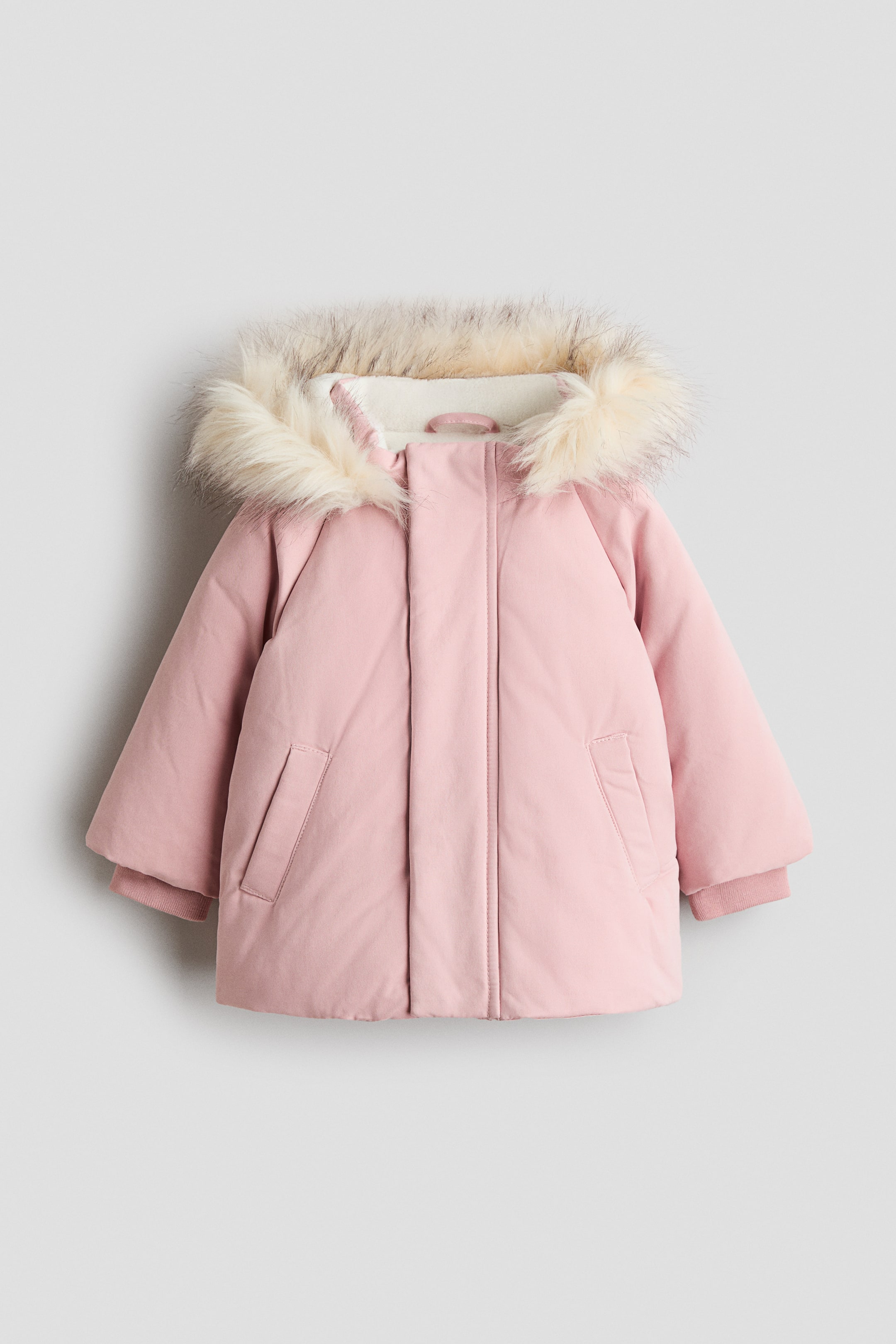 Voir une image plus grande: Une veste matelassée rose avec une capuche bordée de fausse fourrure crème et une doublure intérieure crème, deux poches avant en biais et des poignets côtelés.