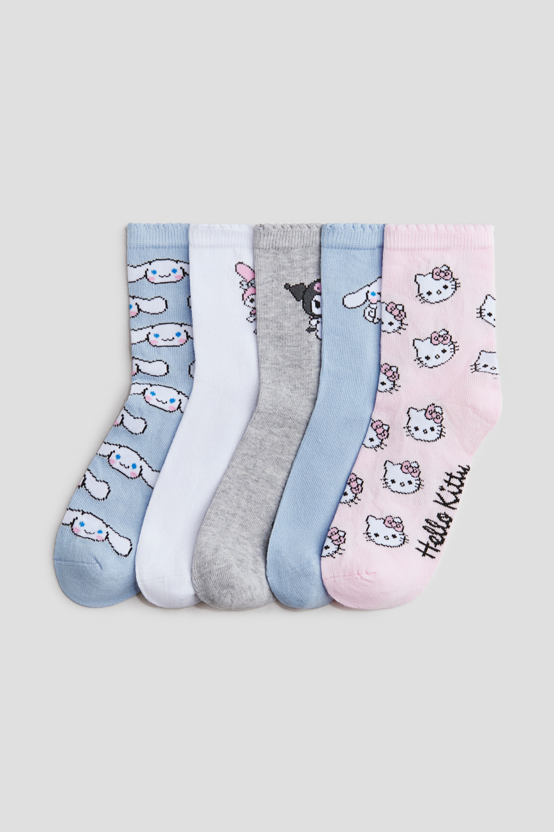 Prikaži veću sliku: Pet pari čarapa od finog pletiva u mešavini pamuka prikazuju svoje prednje strane. Čarape imaju raznovrsne motive, uključujući svetloplave čarape sa Cinnamoroll, belu čarapu sa My Melody, sivu čarapu sa Kuromi, i roze čarape sa licima Hello Kitty i tekstom 'Hello Kitty', sve sa elastičnim rebrastim vrhovima.