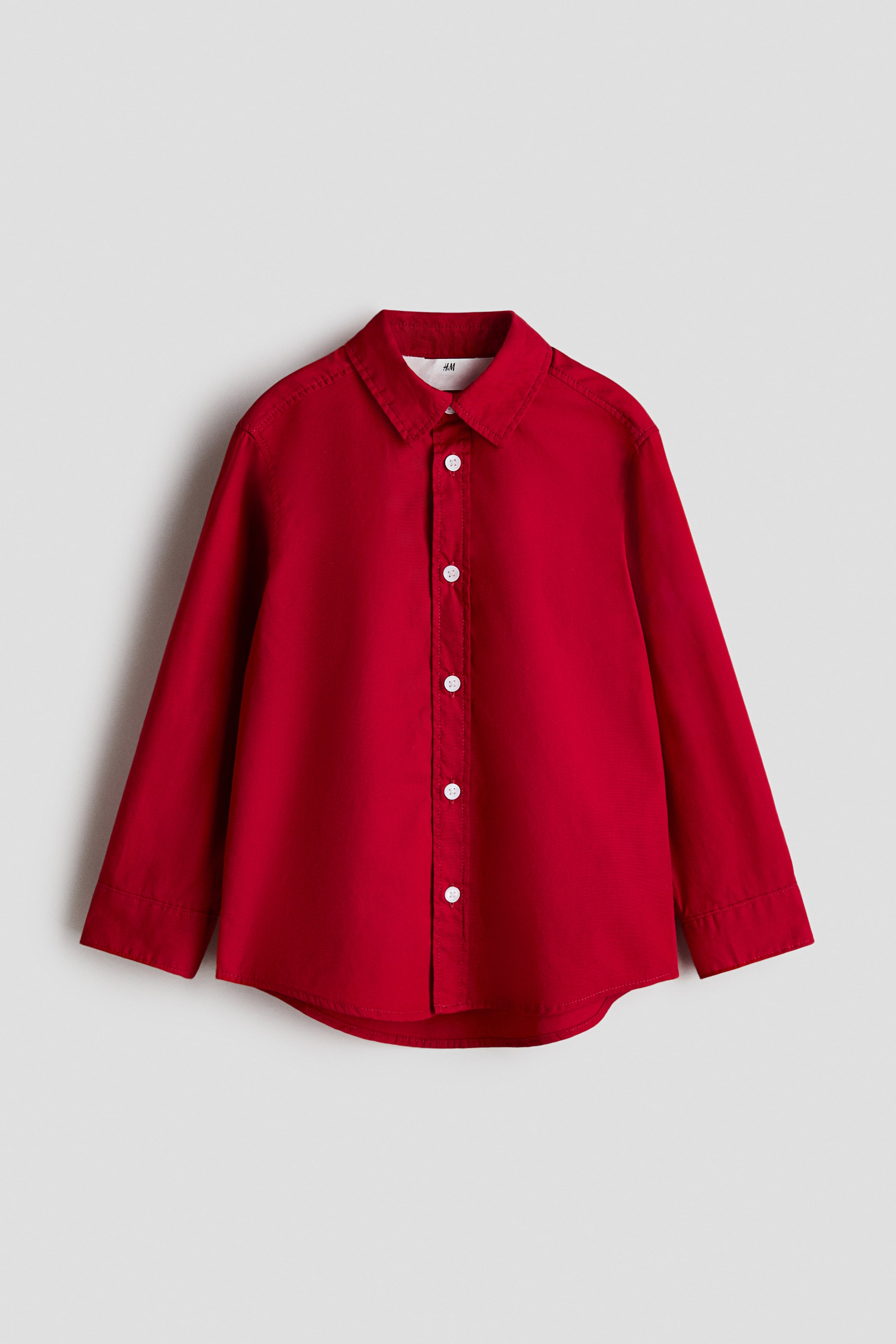View larger image: A red shirt is presenting its FRONT, featuring a turn-down collar and a full button-down front with white buttons. It is designed with long sleeves ending in buttoned cuffs and a gently rounded hem.