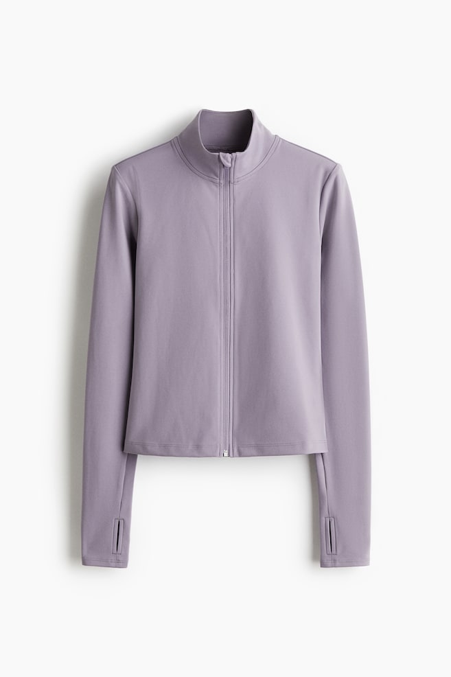 Eine fliederfarbene Sportjacke mit Reißverschluss wird von vorne gezeigt, mit einem Stehkragen, einem durchgehenden Frontreißverschluss und langen Ärmeln mit Daumenlöchern an den Bündchen. Die Jacke ist mit einem verkürzten Saum gestaltet. - 1
