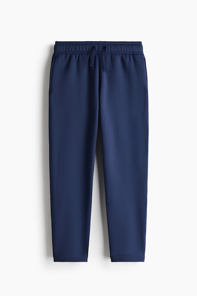 Pantalones deportivos azul marino vistos de frente, que muestran una pretina elÃ¡stica con cordÃ³n a juego. El pantalÃ³n presenta un diseÃ±o de pierna recta con bolsillos laterales sutiles y dobladillos con acabado limpio. - 1