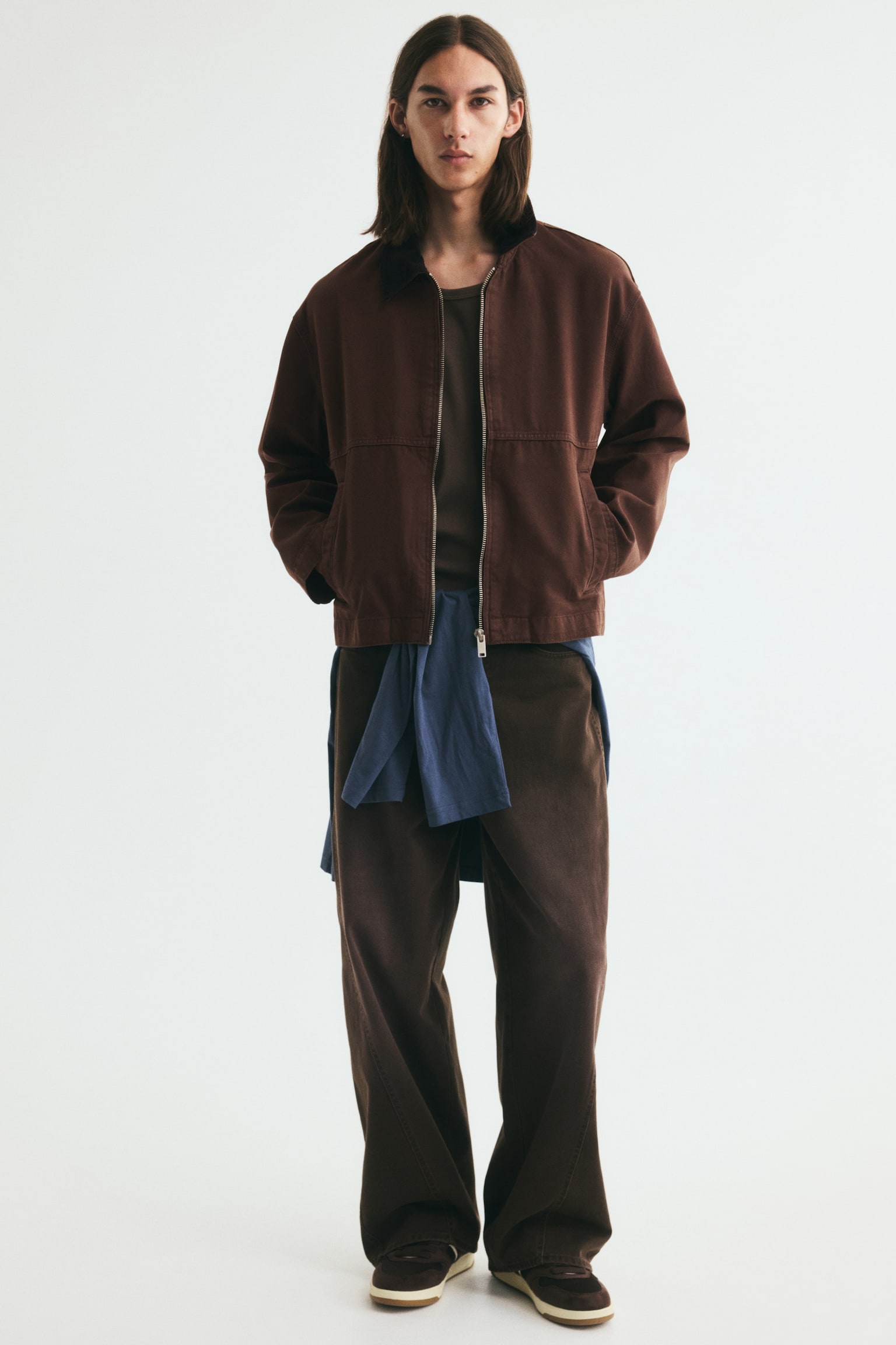 A short workwear jacket in brown cotton canvas is showcased from the front, featuring a contrasting black corduroy collar. A silver-toned zip runs down the front, with two welt front pockets, long sleeves, and a straight-cut hem completing the design. - 1