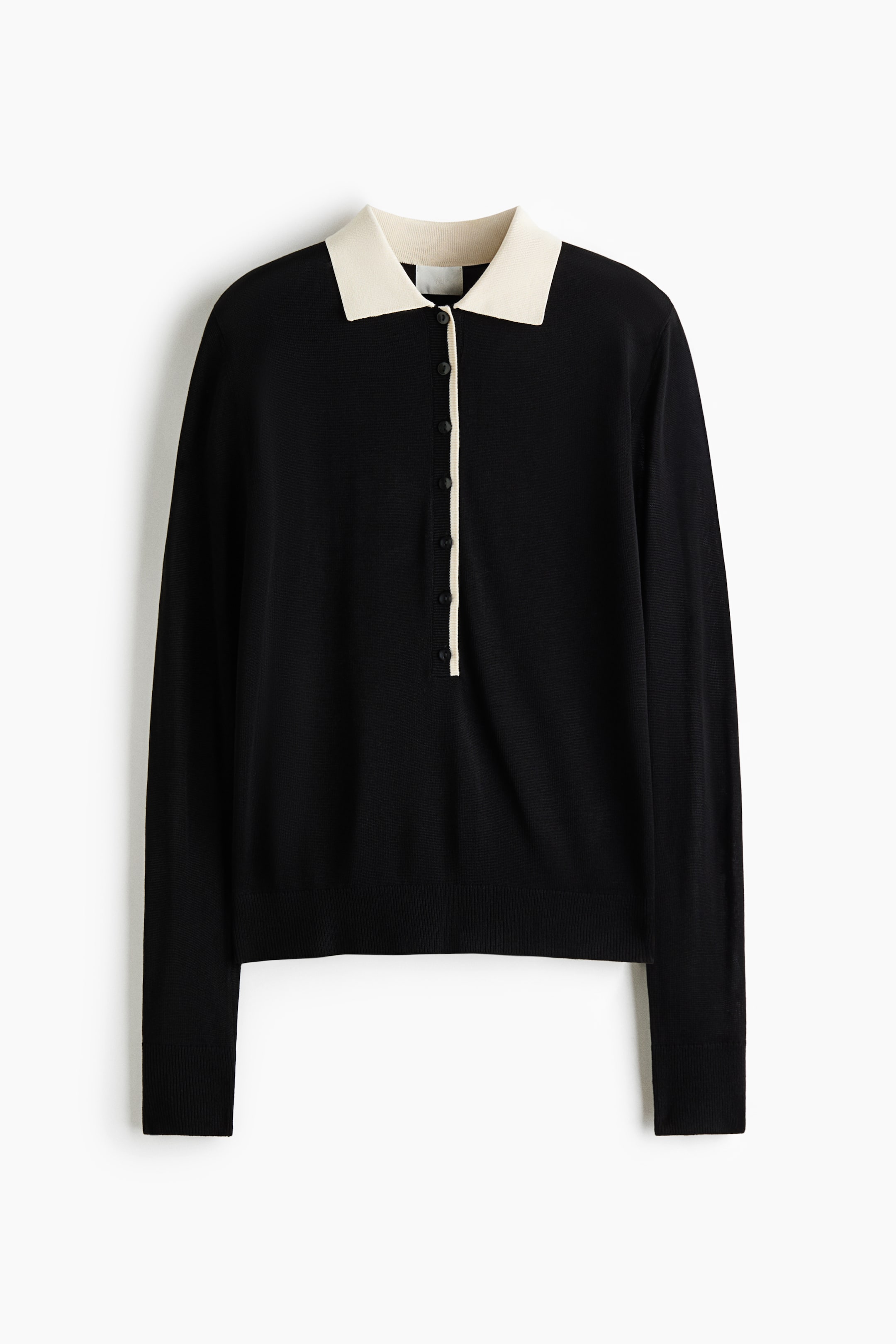 View larger image: A black long-sleeved knit sweater is shown from the front, featuring a contrasting cream-colored polo collar and a partial button placket with a matching cream border. The garment has a fine-knit texture with ribbed cuffs and a ribbed hem.