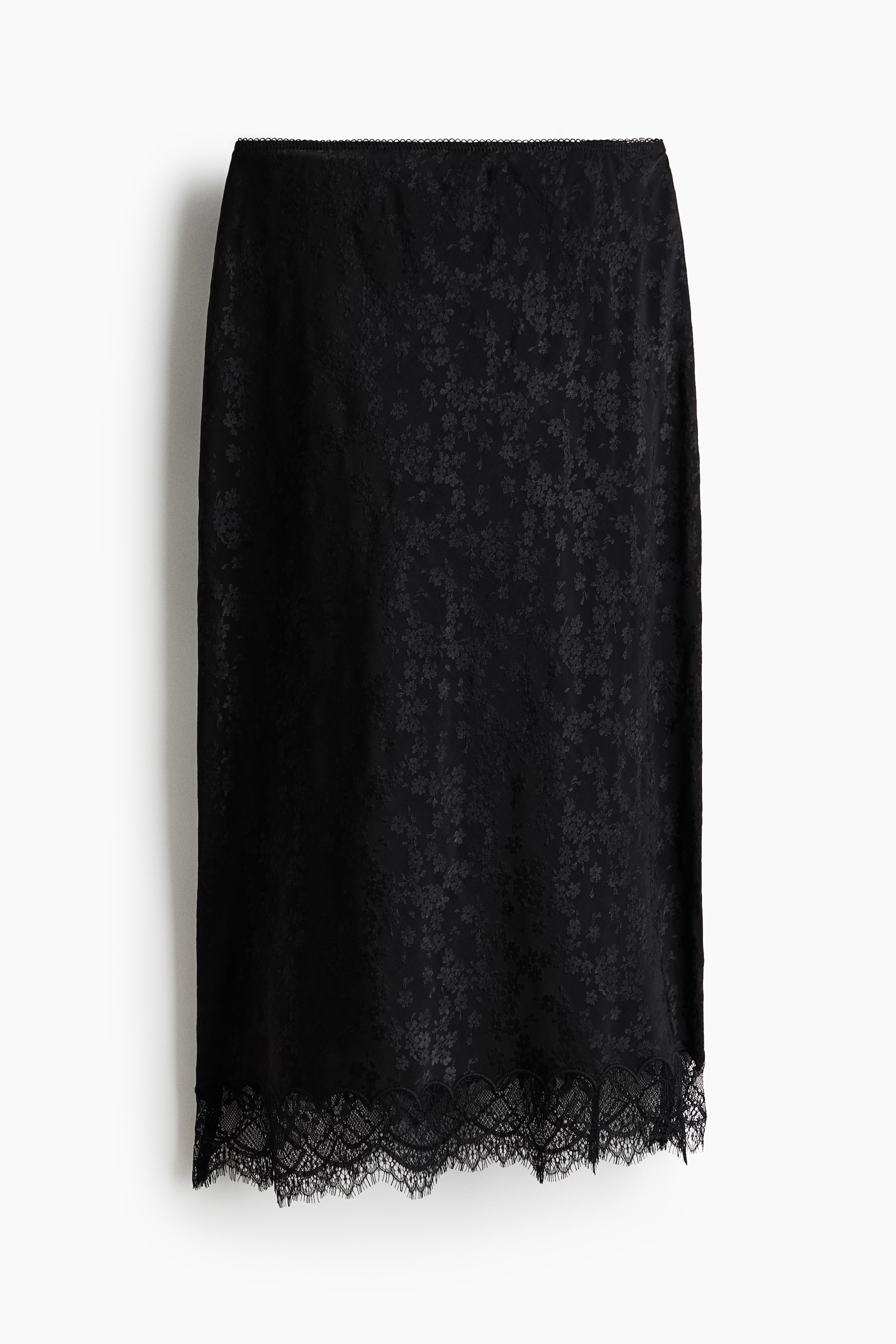 Ver imagen más grande: Una falda negra frontal presenta un sutil estampado de jacquard floral en toda su extensión. Muestra un fino ribete decorativo en la cintura y un delicado encaje negro en el dobladillo.