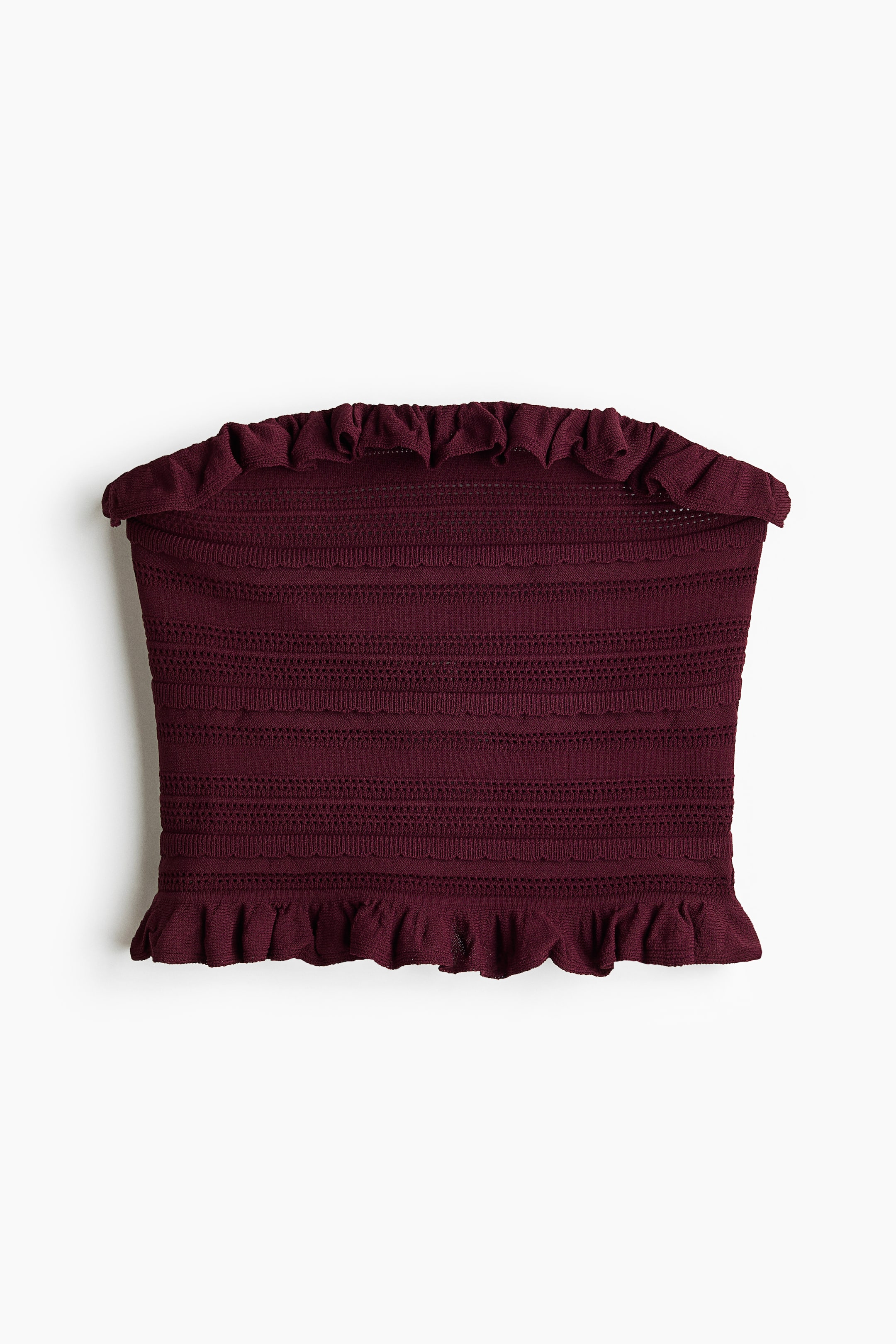 View larger image: A maroon knitted bandeau top showcases a ruffled trim along its top and bottom edges. The front-facing top exhibits shirred detailing throughout its body, with alternating horizontal bands of solid and open-knit patterns.