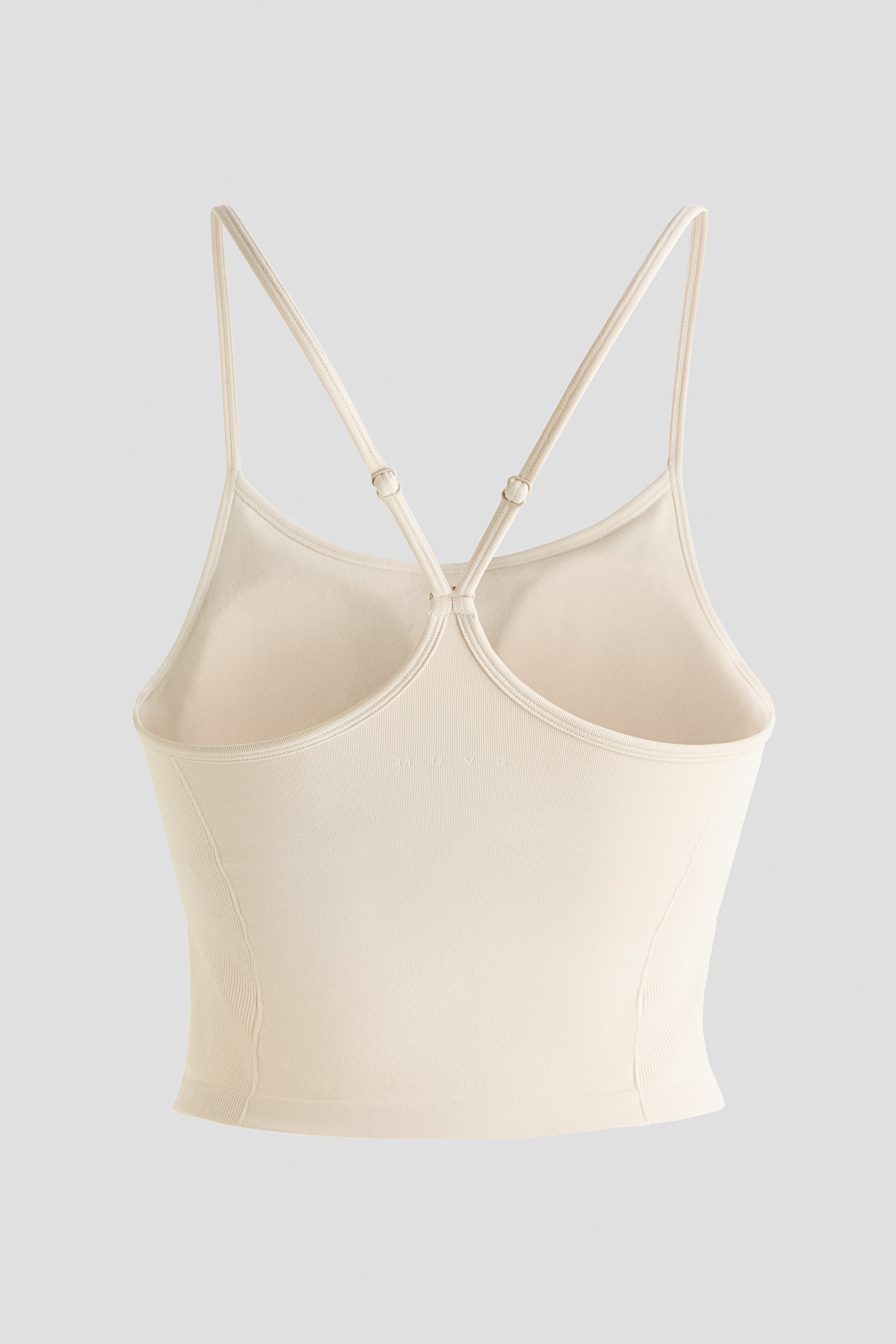 Grotere afbeelding bekijken: Een licht beige crop top wordt van de achterkant getoond, met dunne verstelbare spaghetti bandjes die in een racerback ontwerp kruisen. De halslijn aan de achterkant is laag uitgesneden en de zijkanten en onderzoom zijn geribbeld.