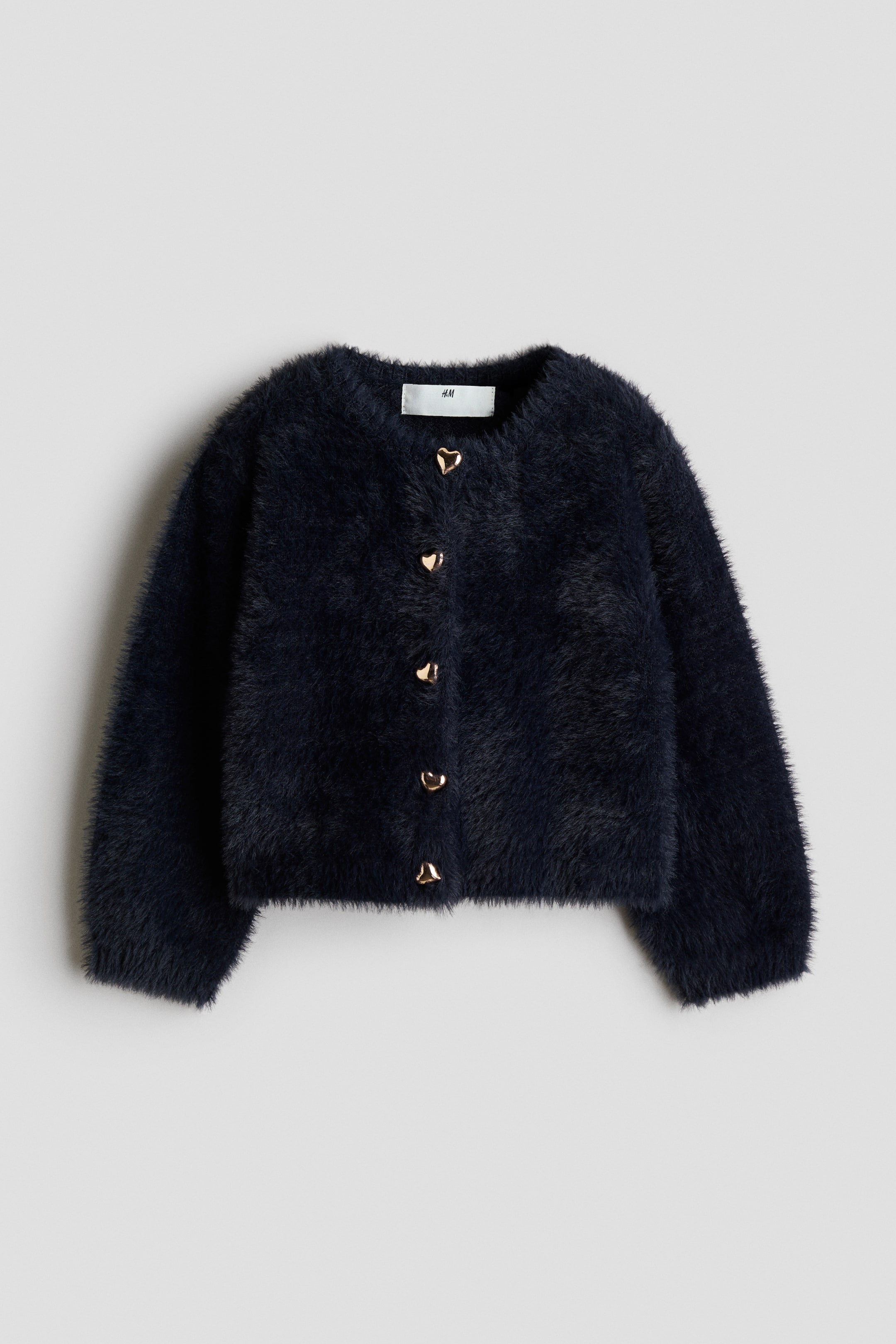 View larger image: A dark navy blue cardigan in a soft, fluffy knit is shown from the front, featuring a round neckline and five gold-toned, heart-shaped buttons down the centre. The cardigan has long, slightly voluminous sleeves and a straight hem.