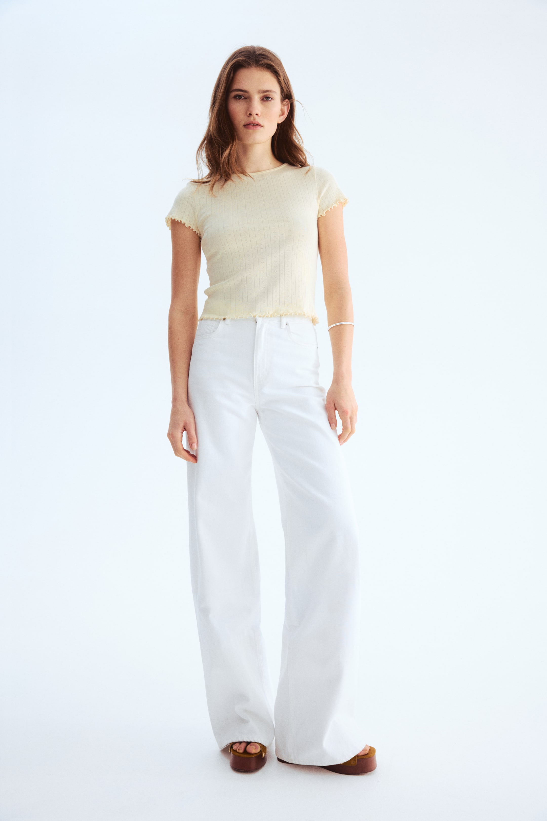 View larger image: "White wide-leg jeans showcase a high-waisted design with a straight, full-length cut that gently gathers at the ankles."