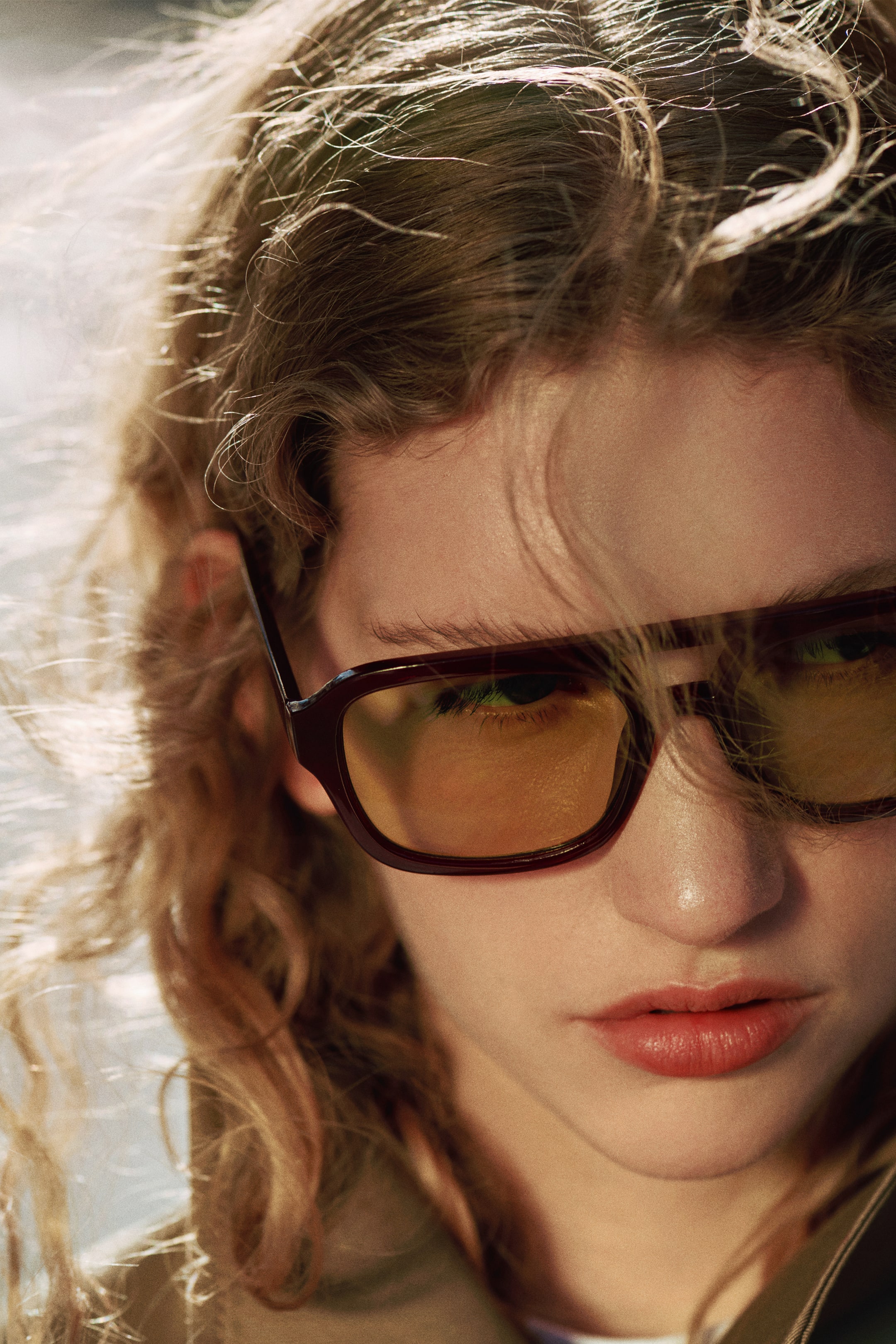 View larger image: Sunglasses with dark brown, rectangular frames and yellow-tinted lenses are being worn, presented from a slight angle. The frames are featuring subtly rounded edges and are fitting closely to the face.
