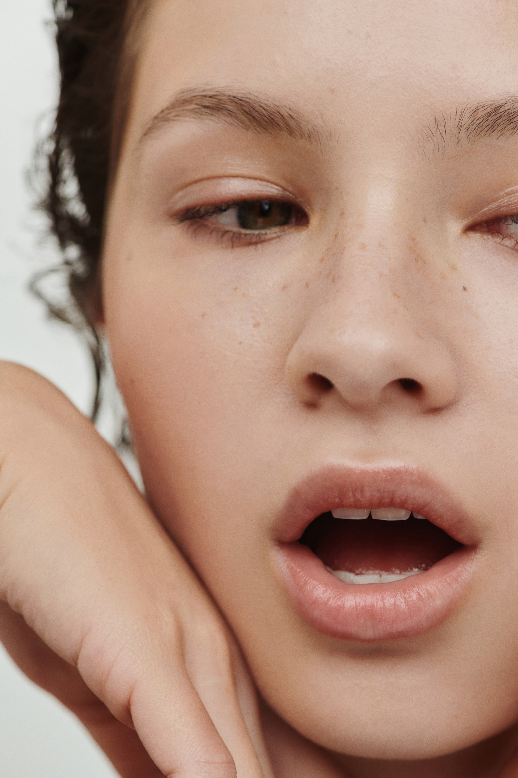 Größeres Bild ansehen: Ein All-in-One-Lipgloss-Balsam wird auf den Lippen des Models getragen und verleiht ihnen ein taufrisches, hochglänzendes Finish sowie einen Hauch natürlicher Farbe, wodurch sie voll und hydratisiert erscheinen.