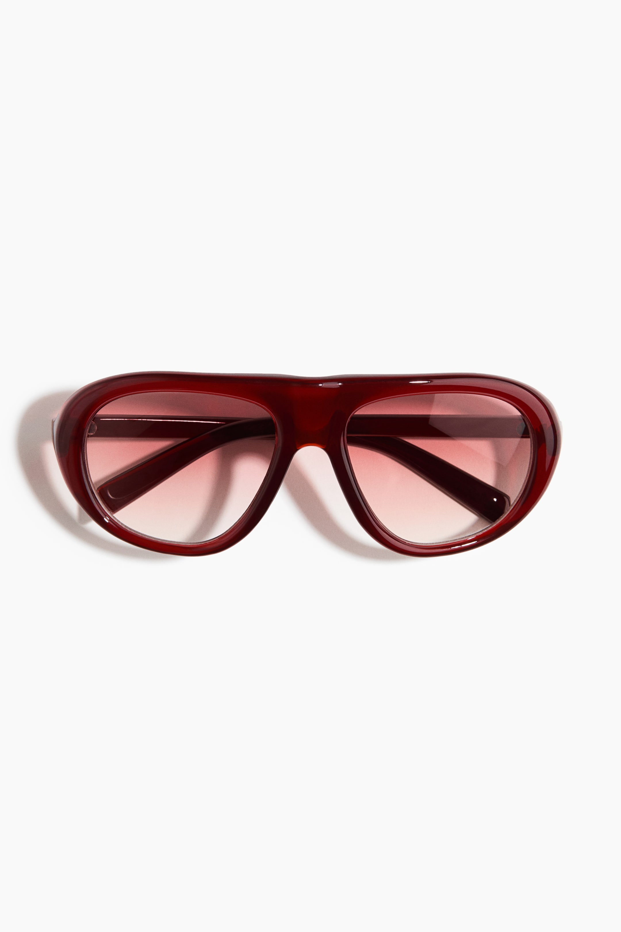 View larger image: "Visor sunglasses are shown from a frontal perspective, showcasing bold, dark red plastic frames and arms, complemented by gradient-tinted plastic lenses."