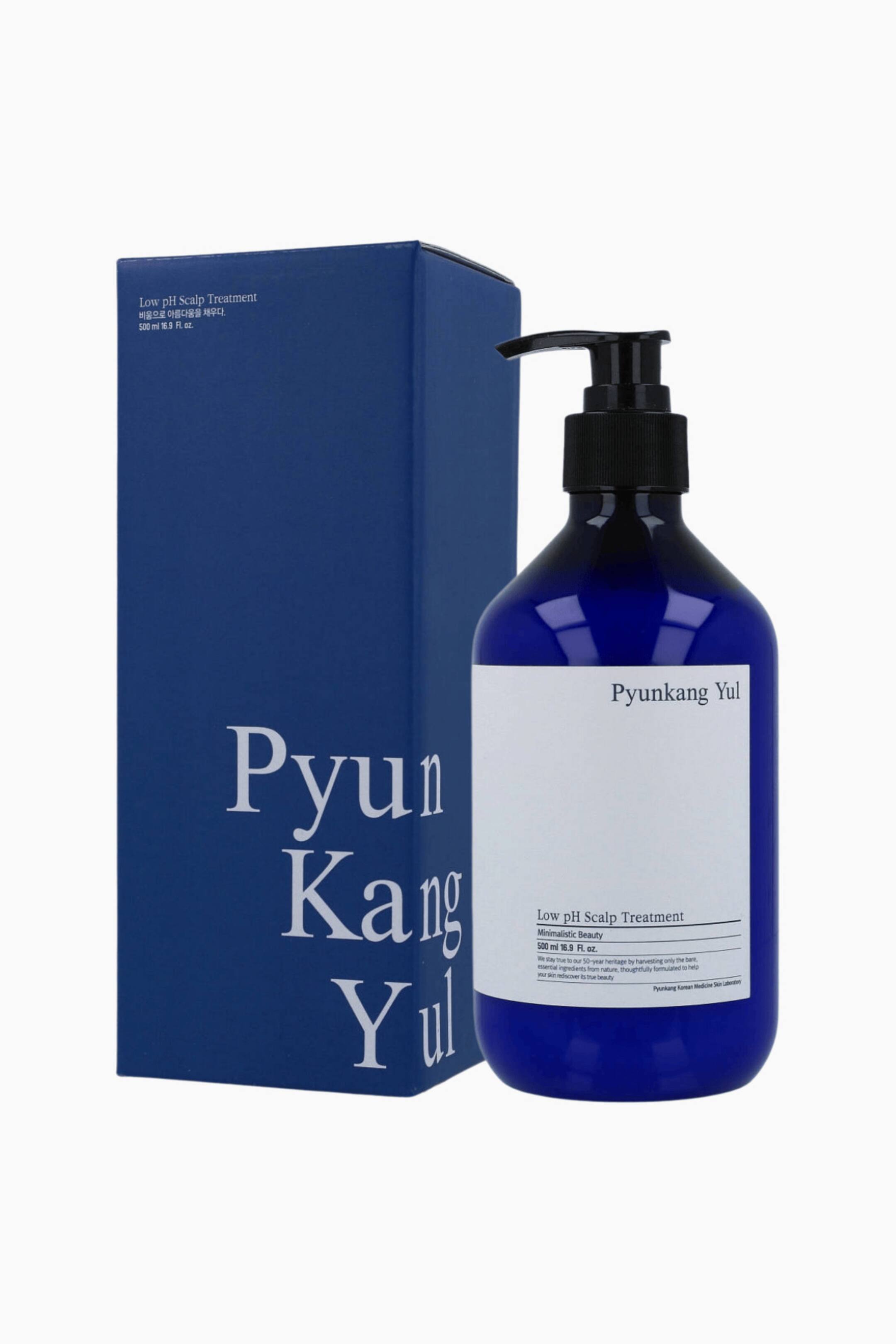 Vis større bilde: En dyp blå Pyunkang Yul Low pH Scalp Treatment-flaske viser en hvit etikett med navnet og volumet sitt, og er toppet med en svart pumpe dispenser. Flasken er vinklet litt til høyre, stående ved siden av sin matchende blå rektangulære eske som har merkevarenavnet på forsiden.