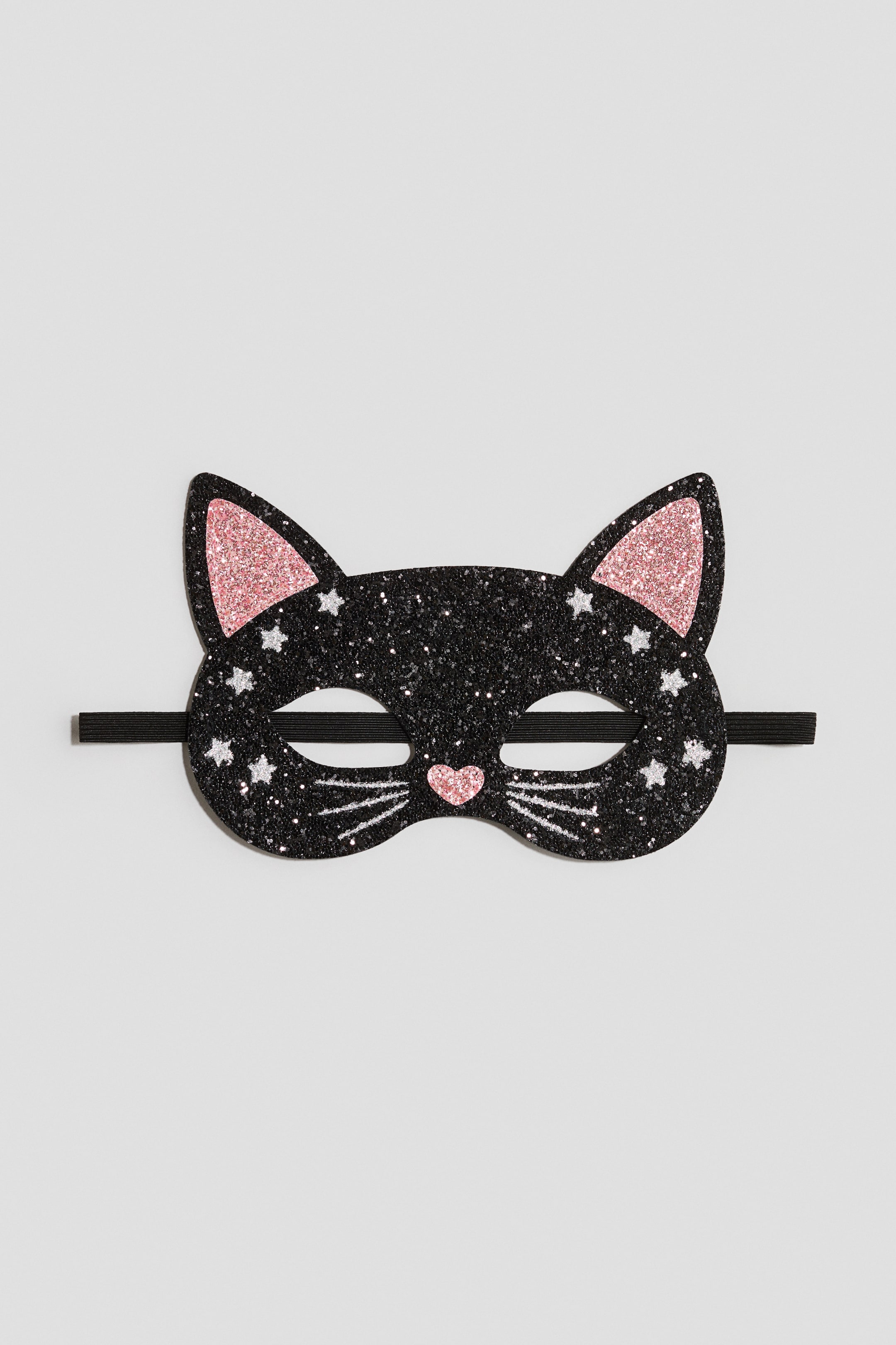Grotere afbeelding bekijken: Een zwart glinsterend masker in de vorm van een kat is naar voren gericht en heeft roze glinsterende binnenoren, een roze glinsterende neus in hartvorm en zilverkleurige glinsterende sterren en snorharen. Aan beide zijden van het masker zit een zwart elastisch bandje.