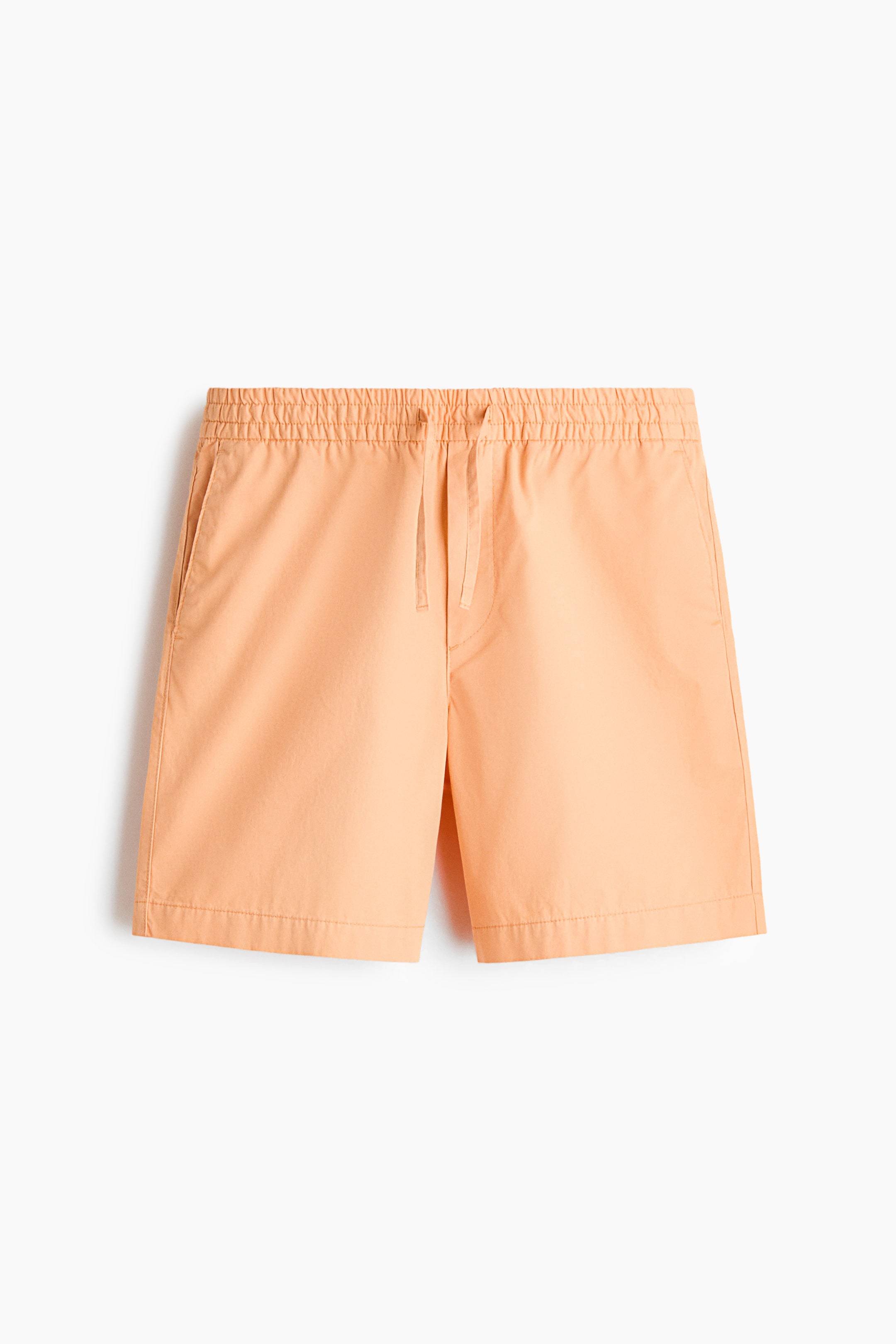 View larger image: The peach-coloured cotton twill shorts are displayed from the front, showcasing an elasticated drawstring waist with a visible drawstring, a mock fly, and diagonal side pockets, all suggesting a relaxed fit.
