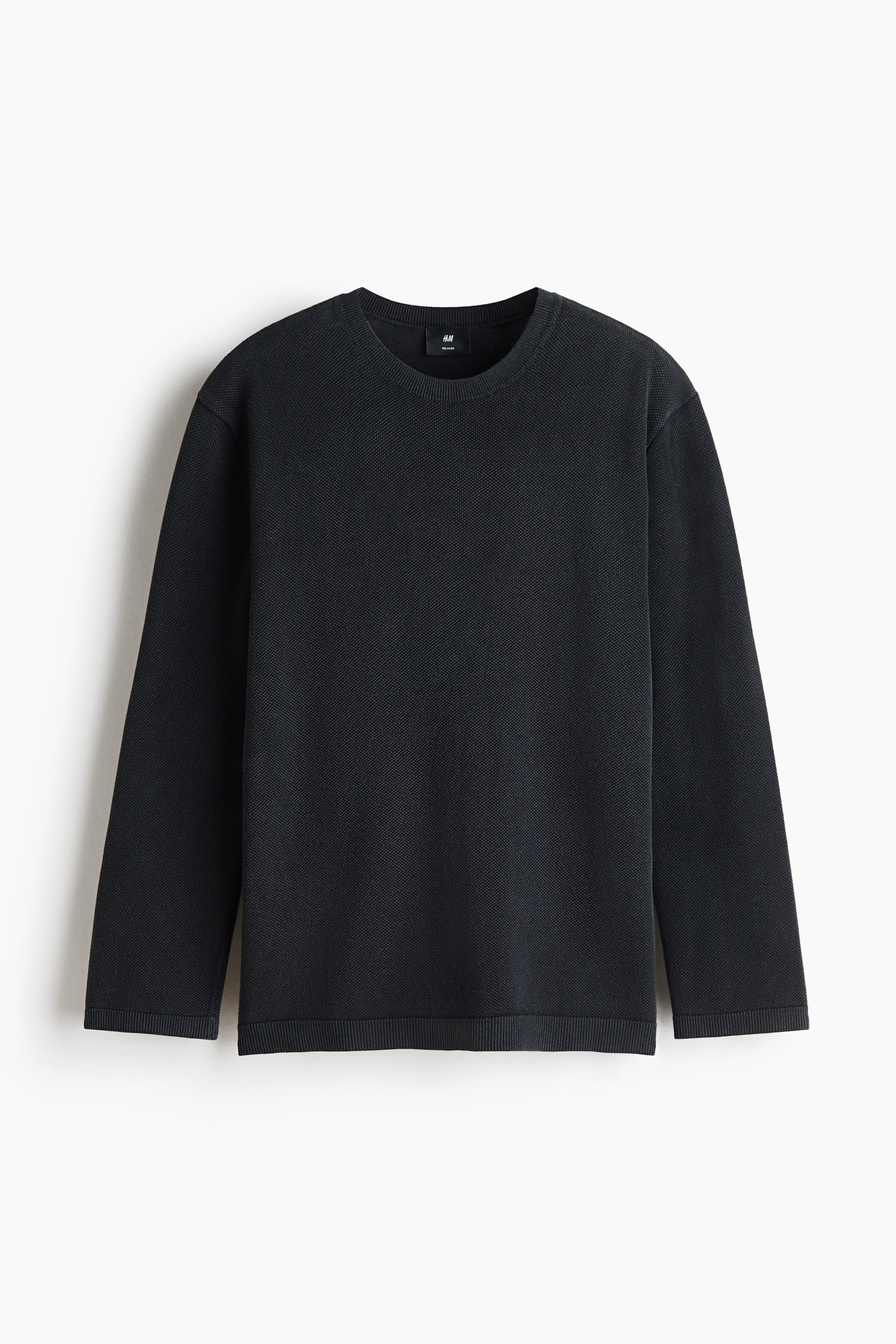 View larger image: A dark grey textured cotton knit sweater is shown facing front, featuring a relaxed fit with a round neckline, long sleeves, and a straight hem. Subtle ribbed knitting details the neckline, cuffs, and hem.