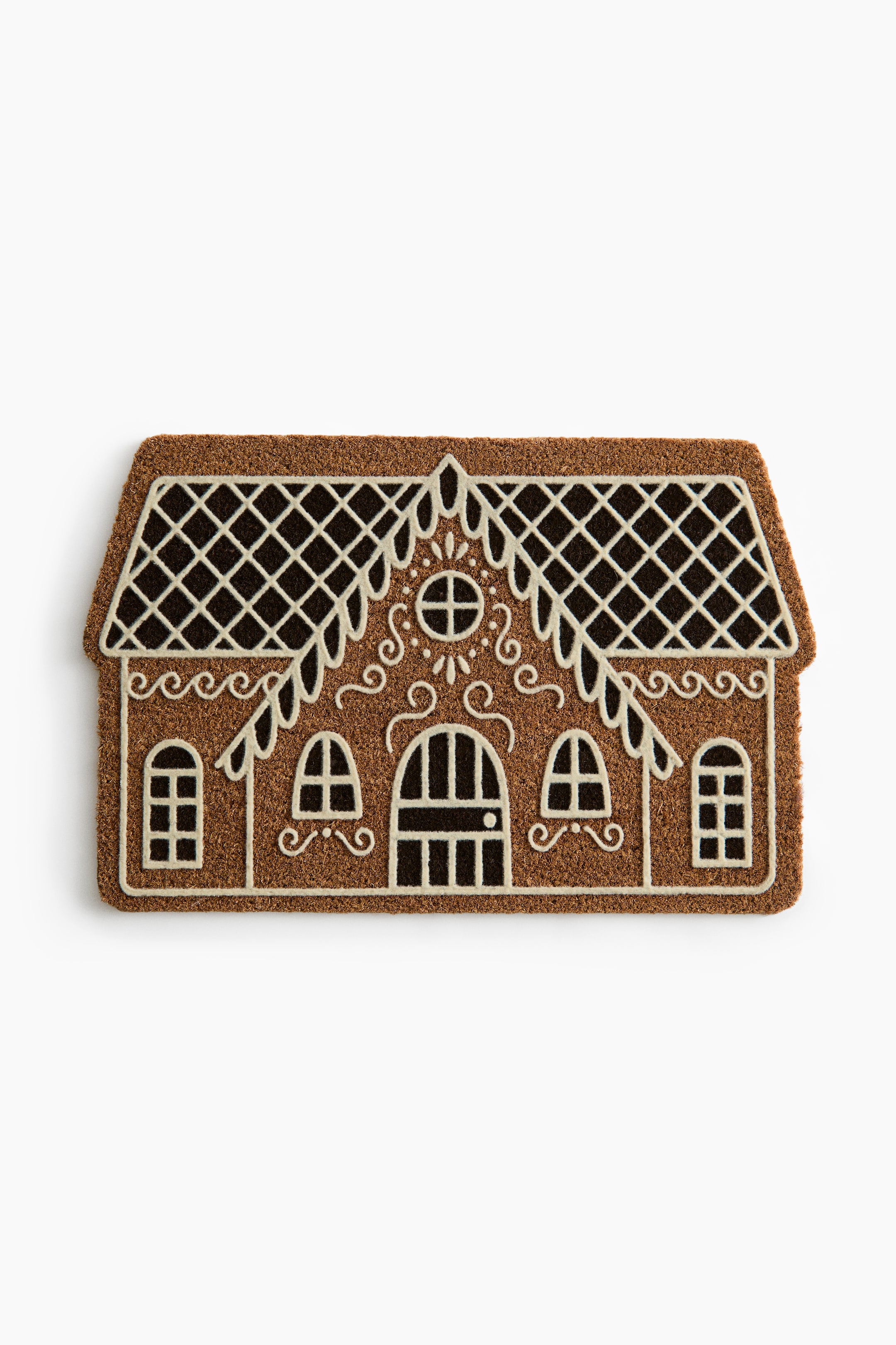 View larger image: A textured coir doormat features a house-shaped design resembling a decorated gingerbread house, shown from a top-down view. The brown mat displays printed cream-white and dark brown details, including a lattice-patterned roof, scalloped icing-like trim, decorative swirls, an arched central door, and multiple windows.